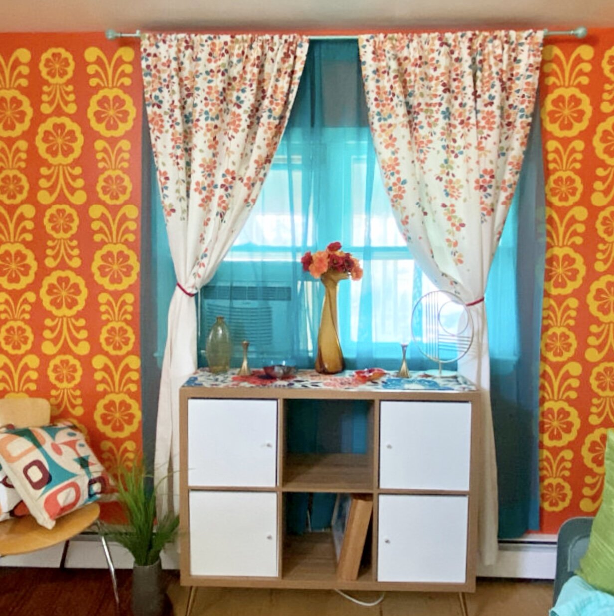 Retro modern flower vinyl wall decals by Wall Star Graphics shown in yellow on an orange living room wall.