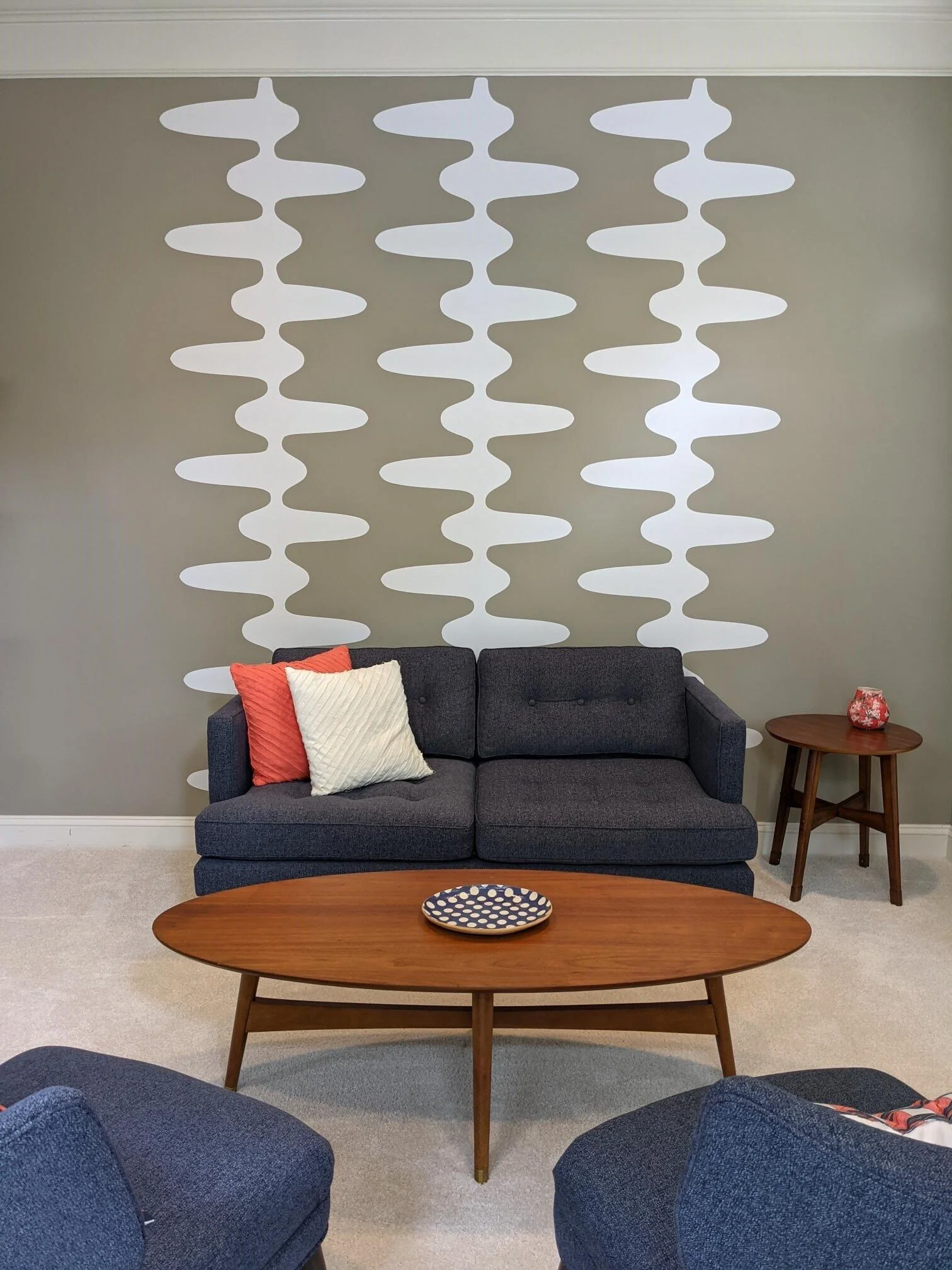 Retro and mid century inspired geometric wall decal pattern shown in white on a grey wall in a mid century modern living room.