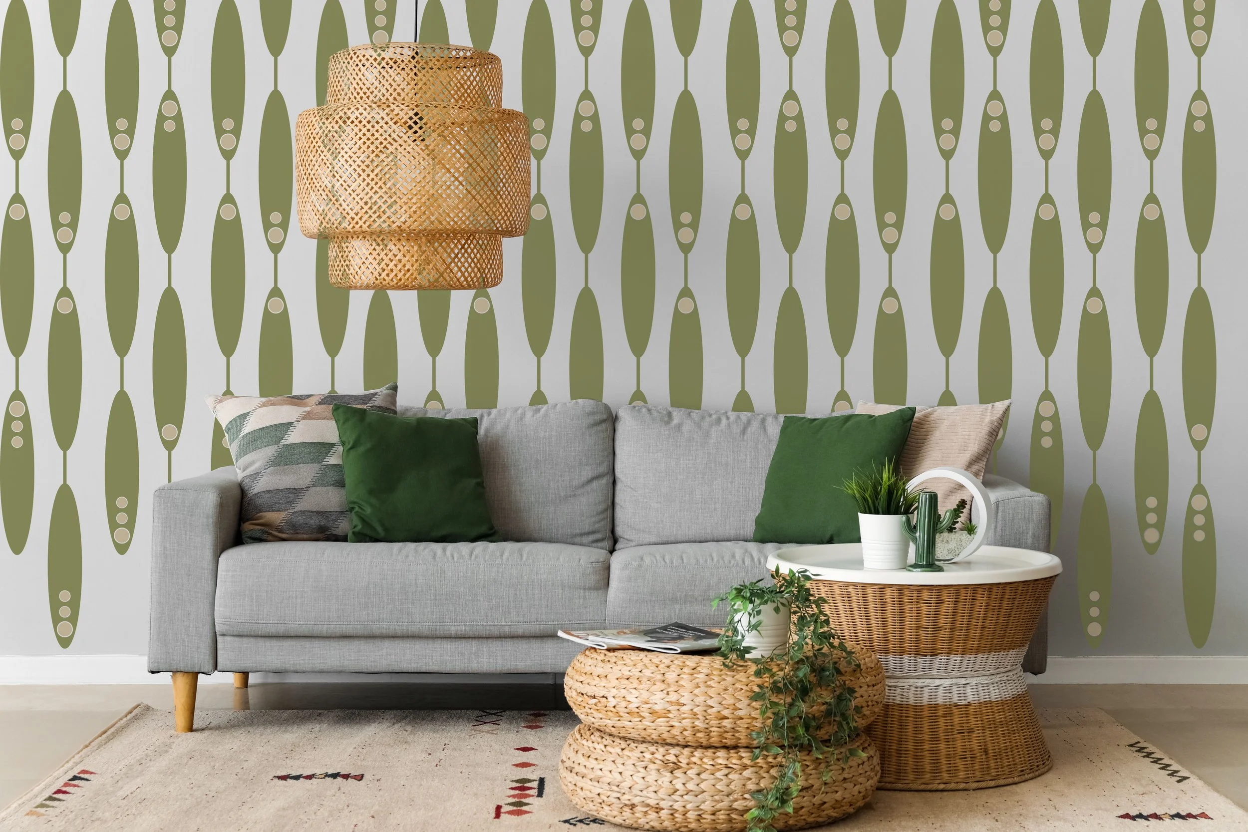 Long oval shapes connected by lines, two color wall decals in olive and beige on a white wall behind a grey couch in a modern living room.