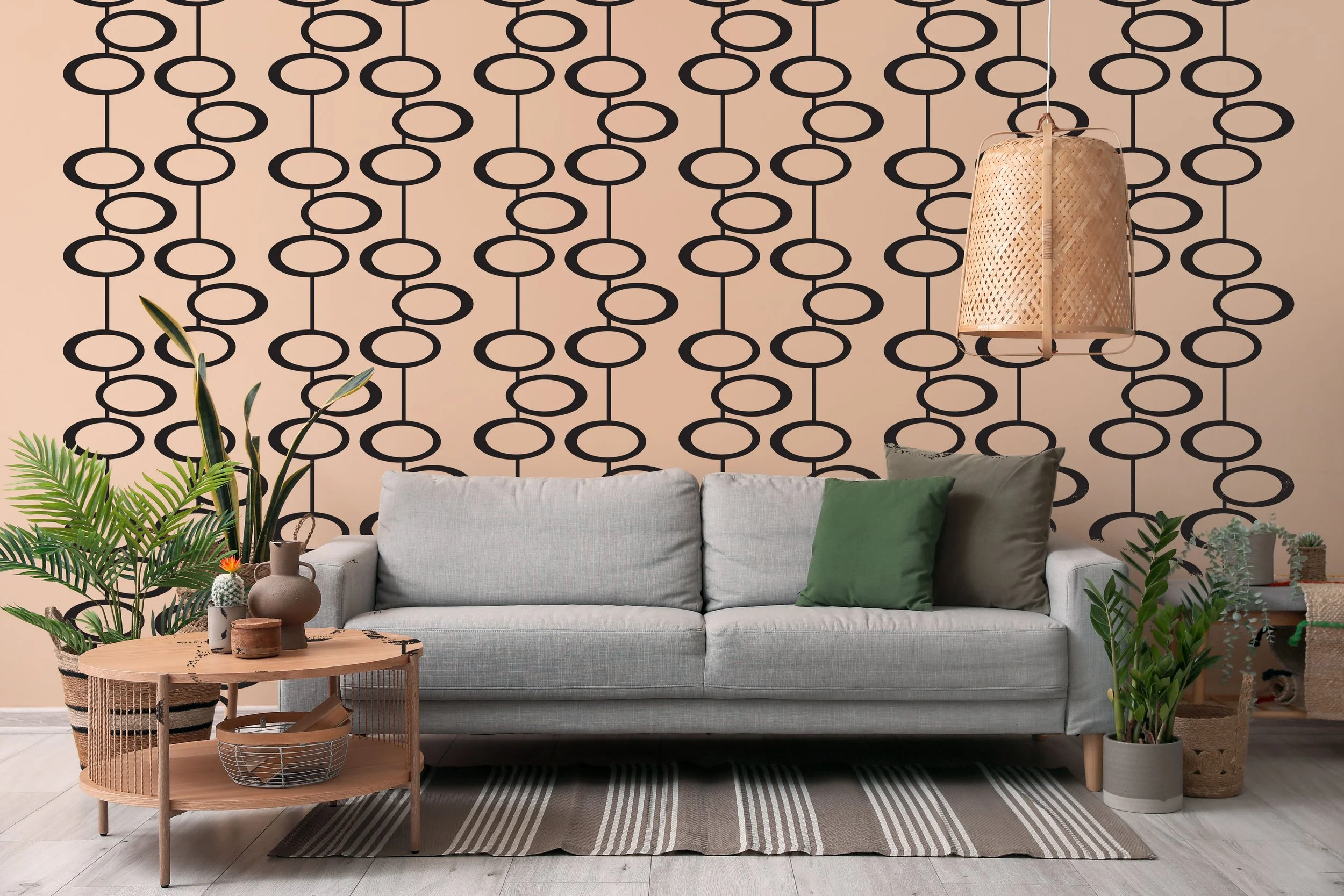 Geometric oval chain wall decal in black on a light tan wall behind a mid century light grey couch.