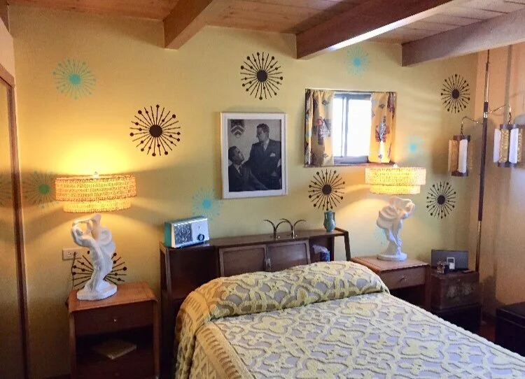 Atomic starburst wall decals in dark brown and turquoise in a mid century primary bedroom.
