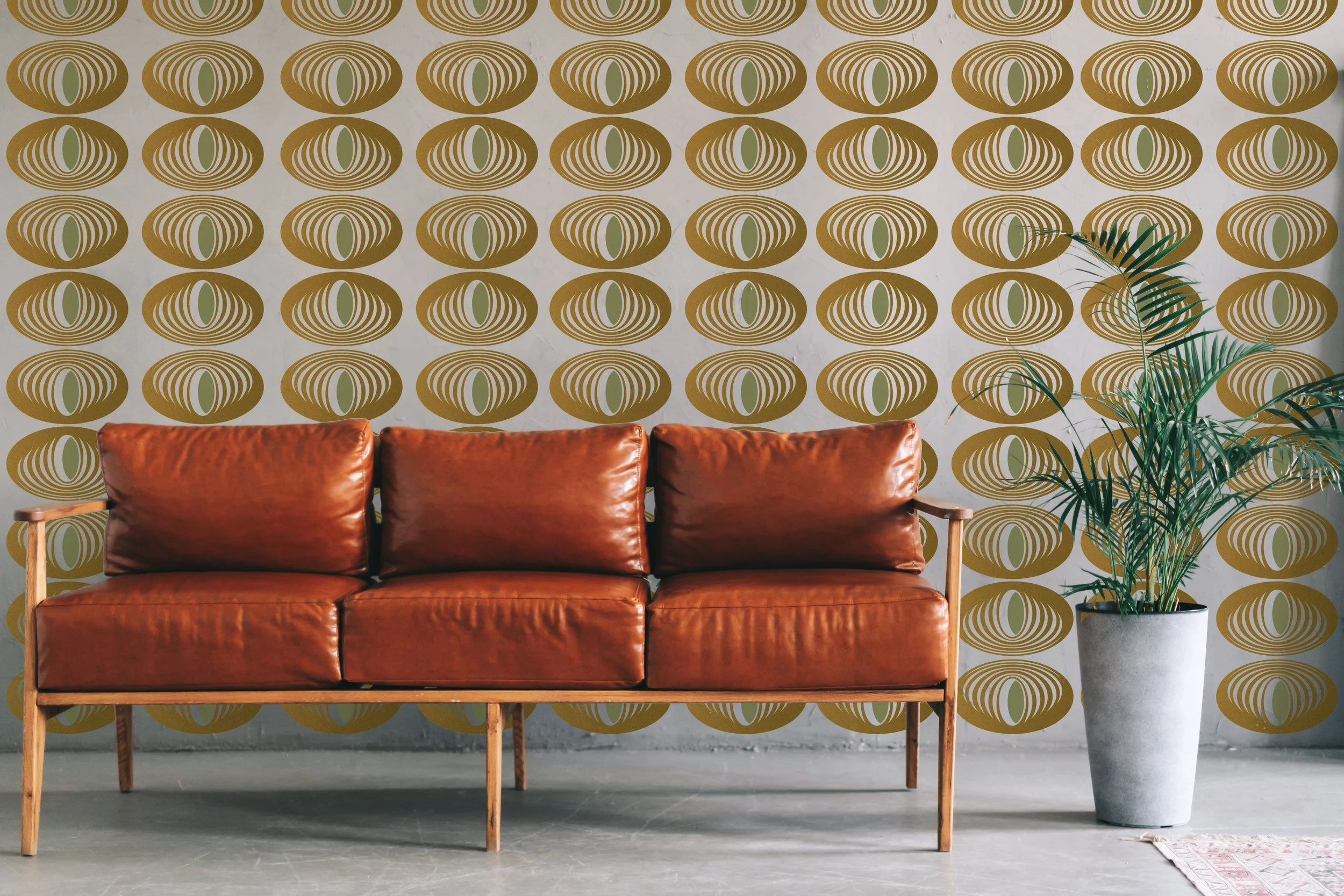 Stylish two color metallic gold and olive wall decals in a geometric oval repeatable pattern styled on a wall behind a burnt orange leather modern couch.