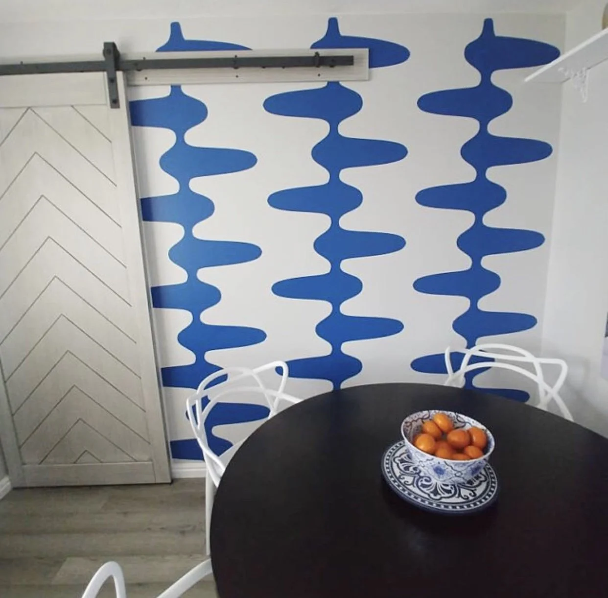 Retro and mid century inspired geometric wall decal pattern shown in blue on a white wall in a modern dining room.