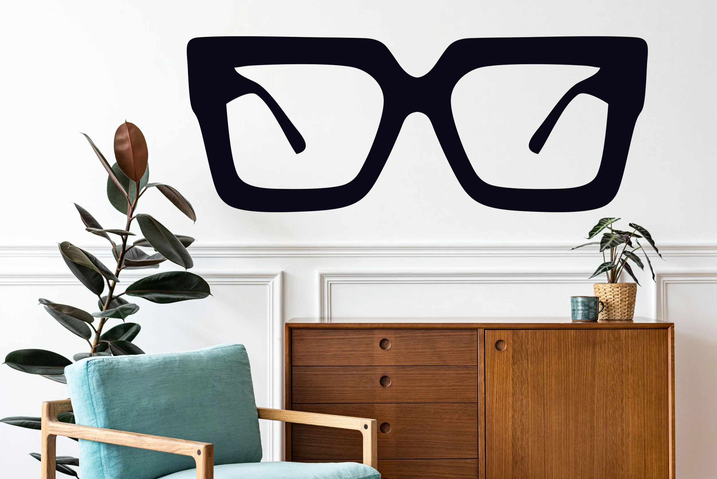 Mod eyeglasses shown in black on a white wall above a side table and chairs.