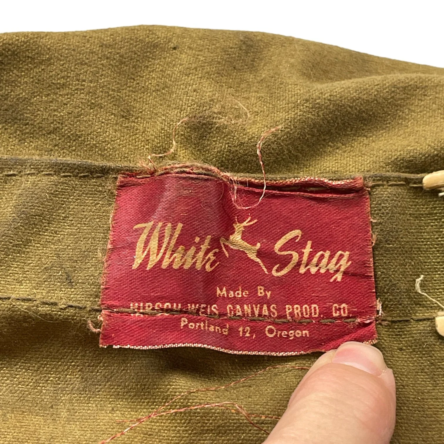 A label on a vintage White Stag trapper's style Army green backpack with wooden frame made by Hirsch Weis Canvas Prod. Co., Portland, Oregon. Made in USA