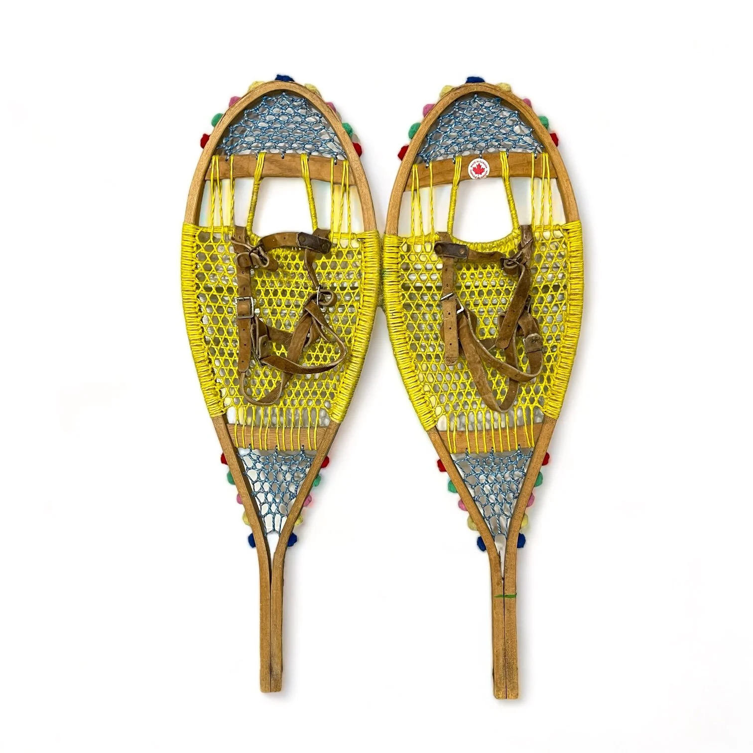 Yellow and blue wooden vintage snowshoes with leather straps.