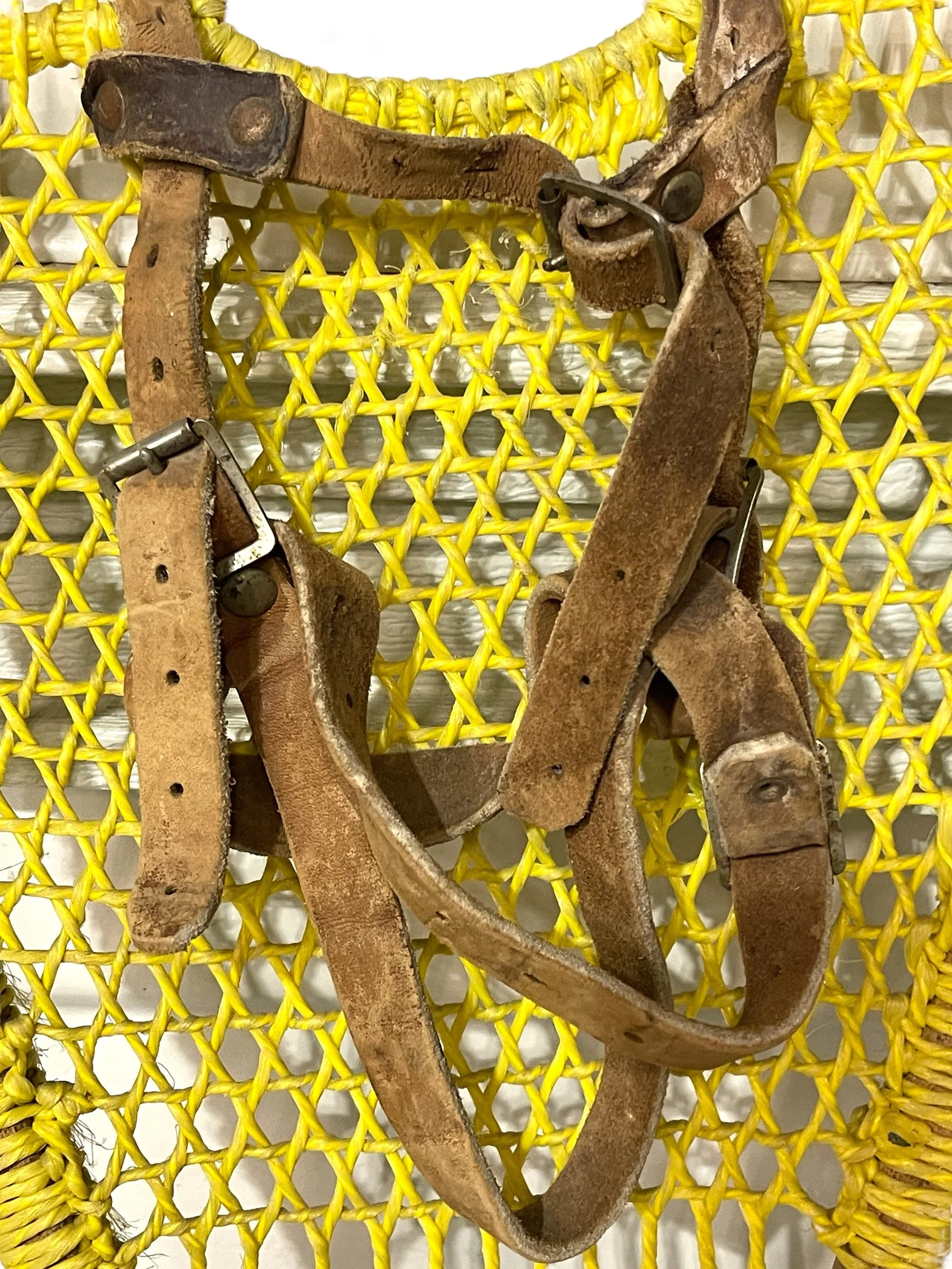 Yellow and blue wooden vintage snowshoes with leather straps.