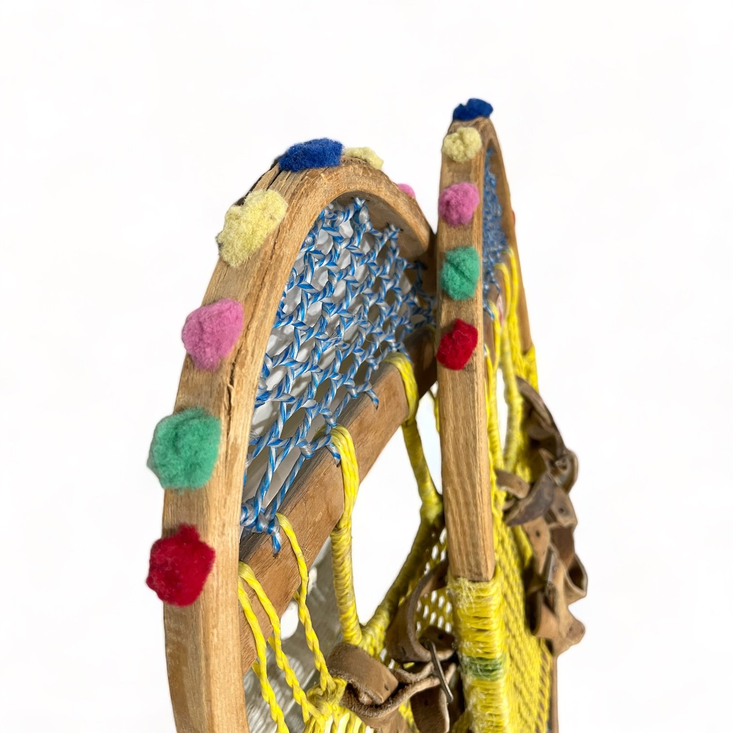 Yellow and blue wooden vintage snowshoes with leather straps.