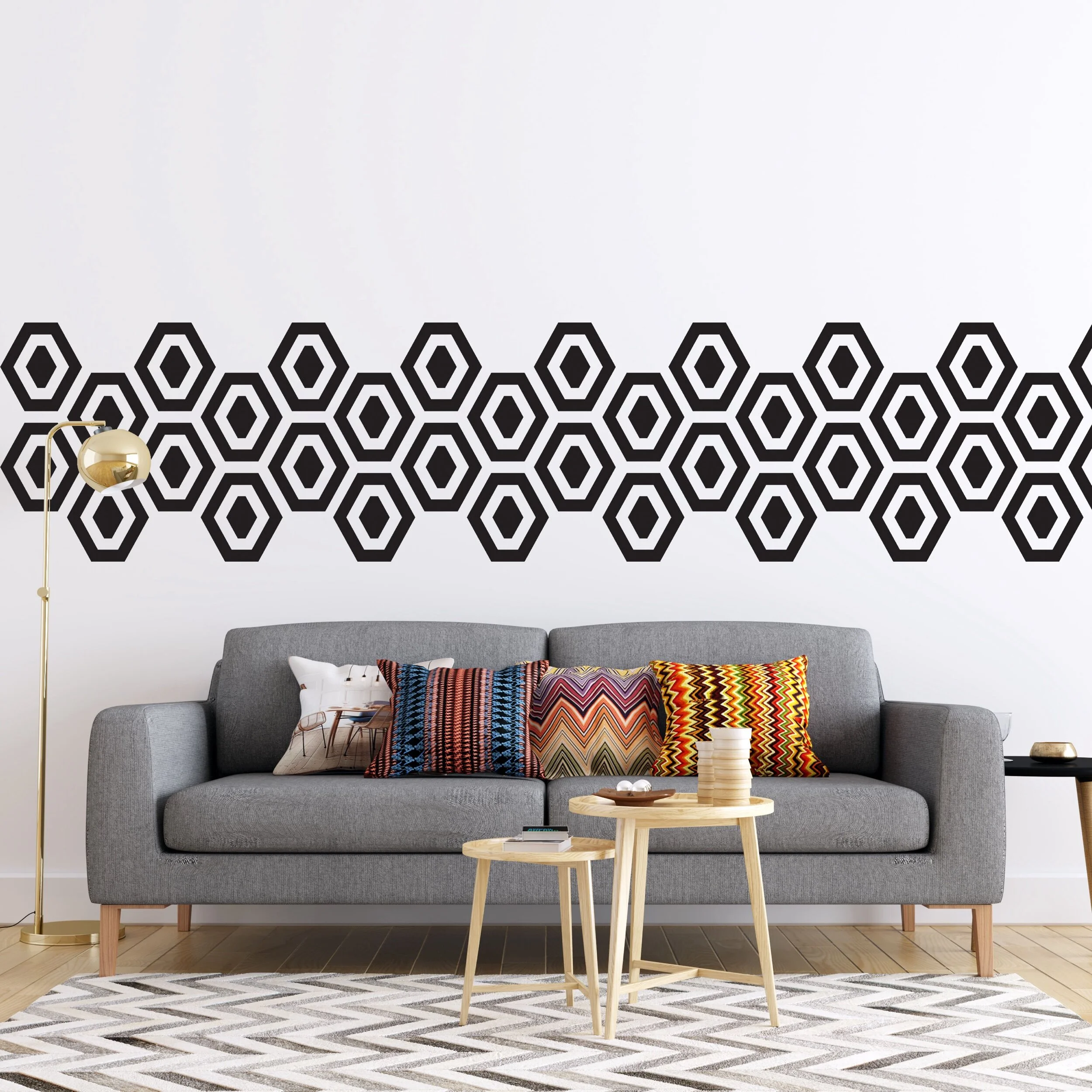 Hexagon geometric pattern vinyl wall decals in black on white wall behind a mid century couch with colorful throw pillows.