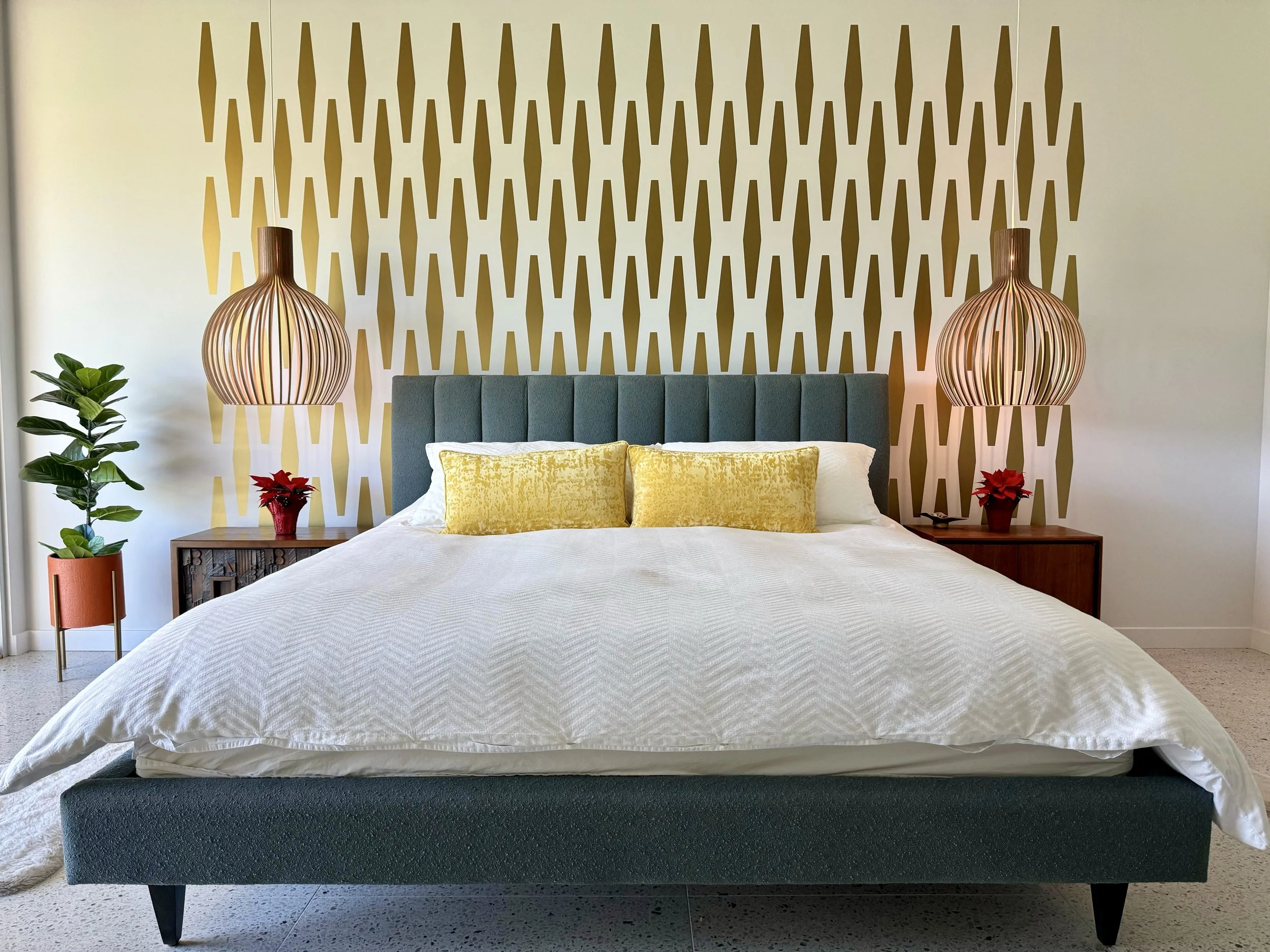 Geometric wall decal pattern in the shape of an elongated hexagon, shown in metallic gold on a white wall of a mid century modern primary bedroom.