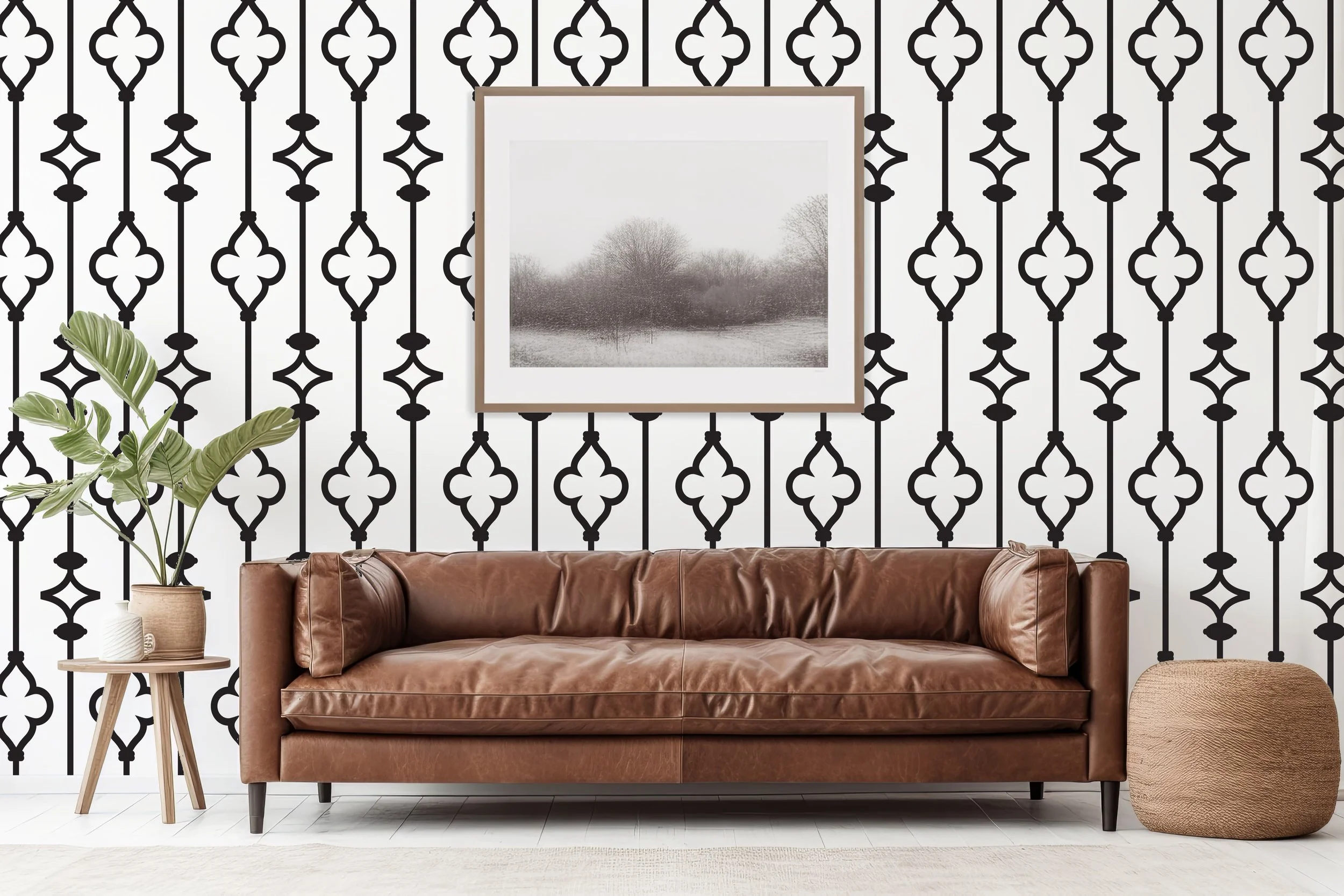 Stylish geometric wrought iron scroll pattern wall decals shown on a white wall with minimalist artwork behind a brown leather couch, pouf ottoman, and a side table with potted palm leaf plant.