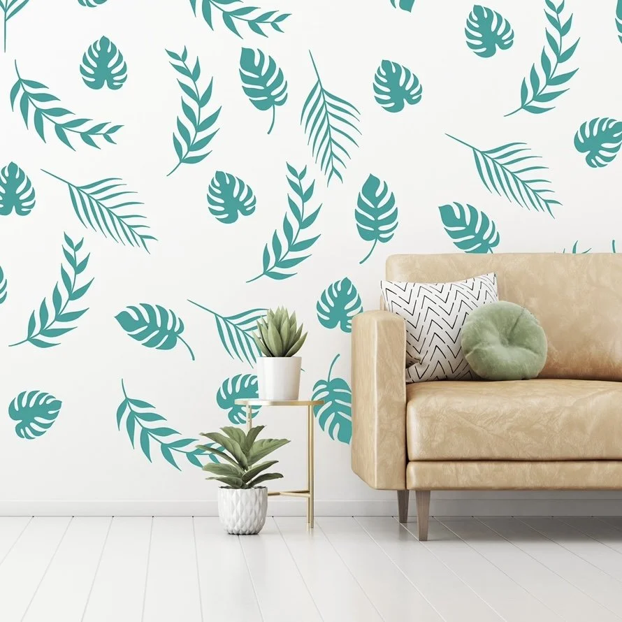 Palm leaf vinyl wall decals in turquoise on a white wall behind a modern leather couch with potted succulents.