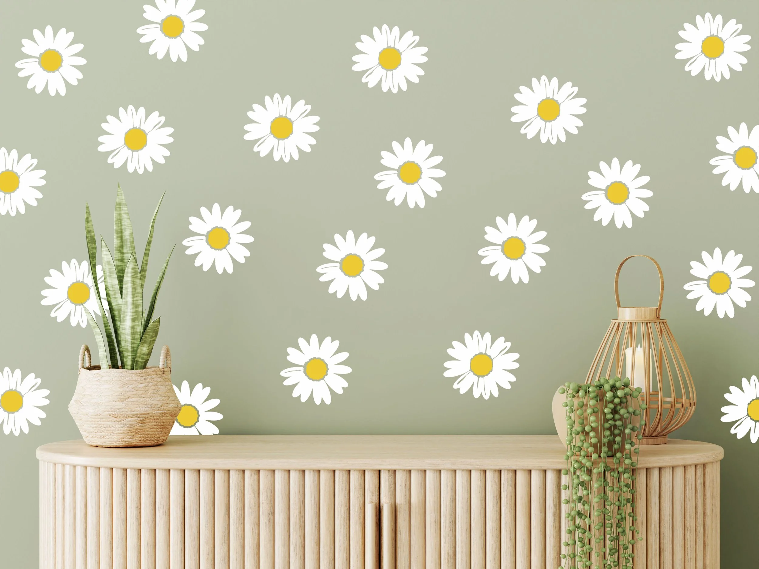 White daisy wall decals with a yellow center on a sage green wall with a light wood modern credenza, a wicker candle lantern, and a potted succulent.