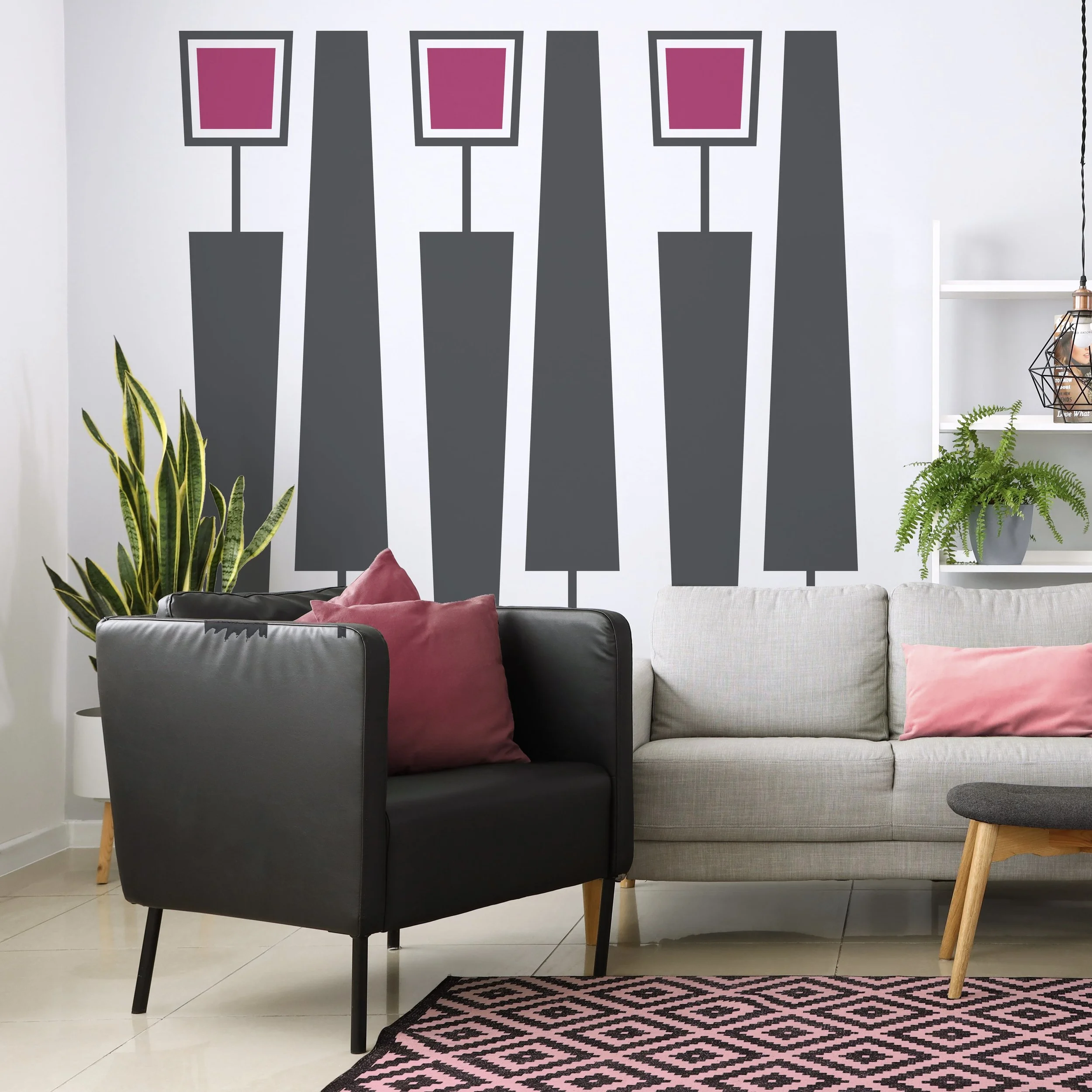 Geometric wall decals in the shapes of squares and trapezoids in dark grey and pink on the wall of a modern living room.