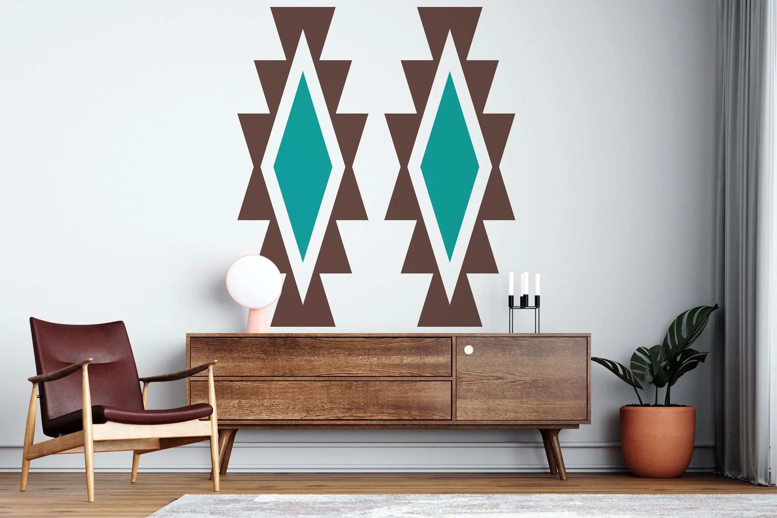 Large Aztec geometric shapes wall decal shown in dark brown and turquoise on a white wall behind a wooden credenza, mid century chair, and potted tropical plant.