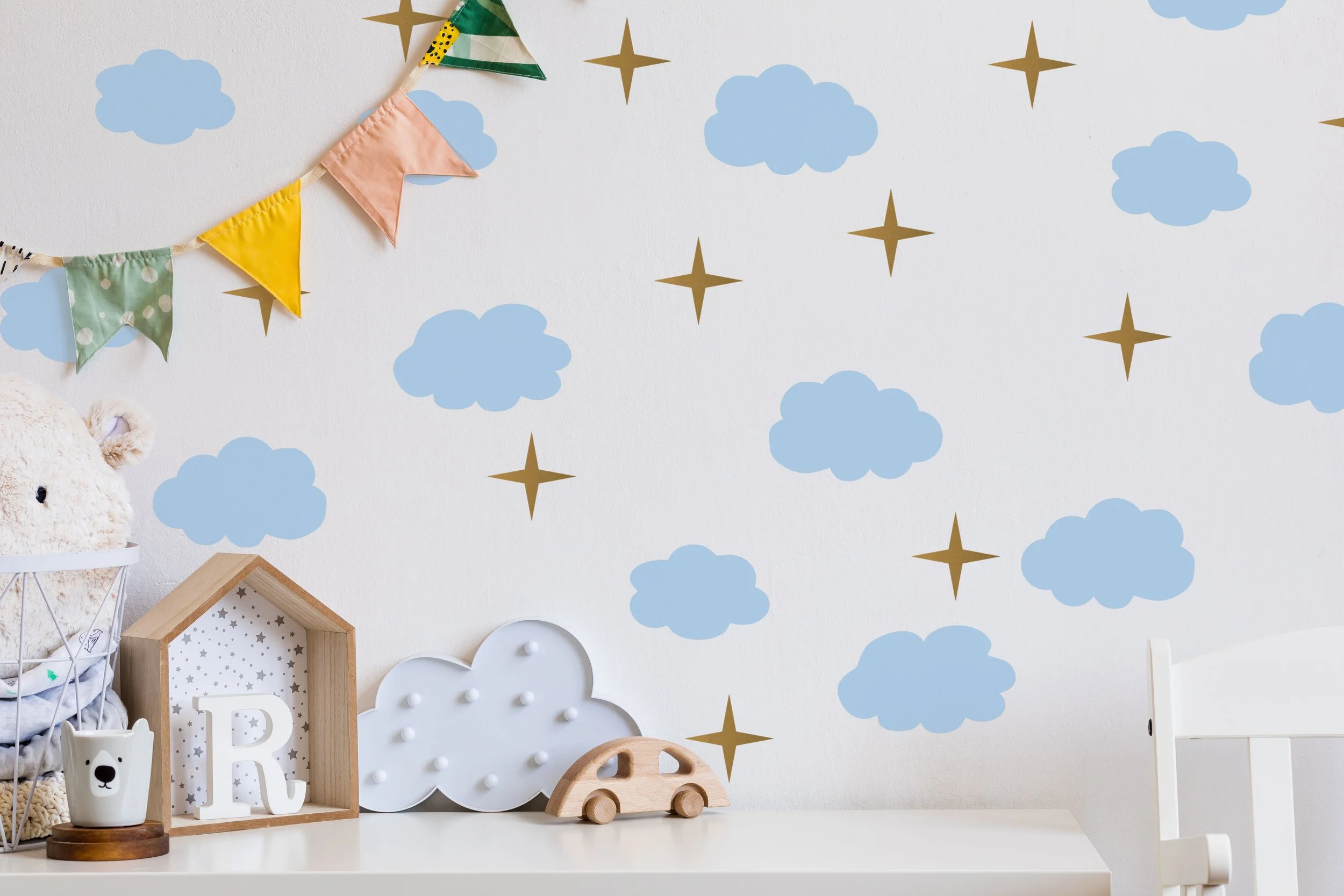 Puffy clouds and atomic stars peel and stick removable wall decals in powder blue and gold styled in a kids room.