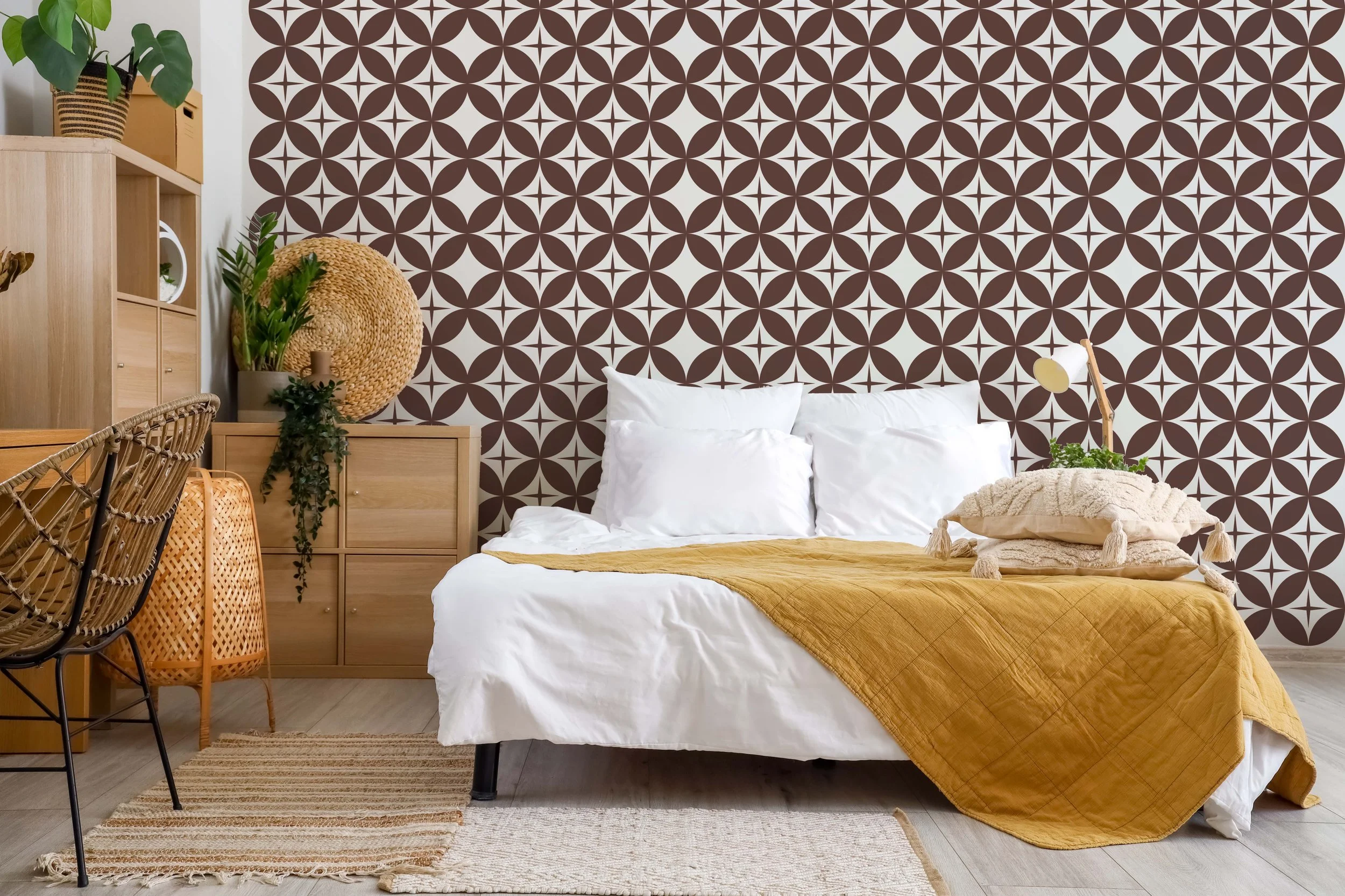 Geometric starburst pattern wall decal in brown on a white wall behind a bed in a boho styled bedroom.