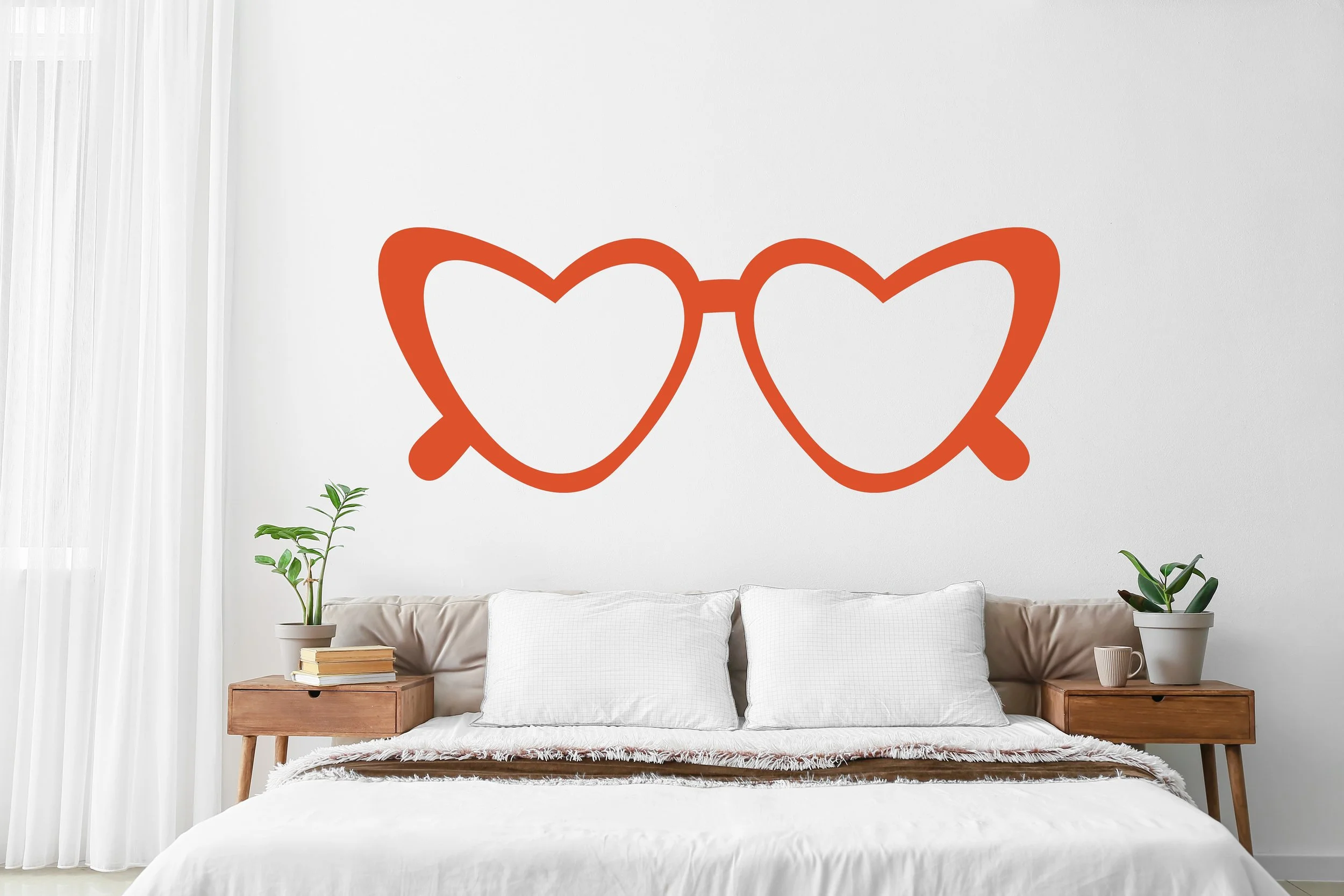 Contemporary heart shaped glasses wall decal in orange installed on a white wall of a modern bedroom.
