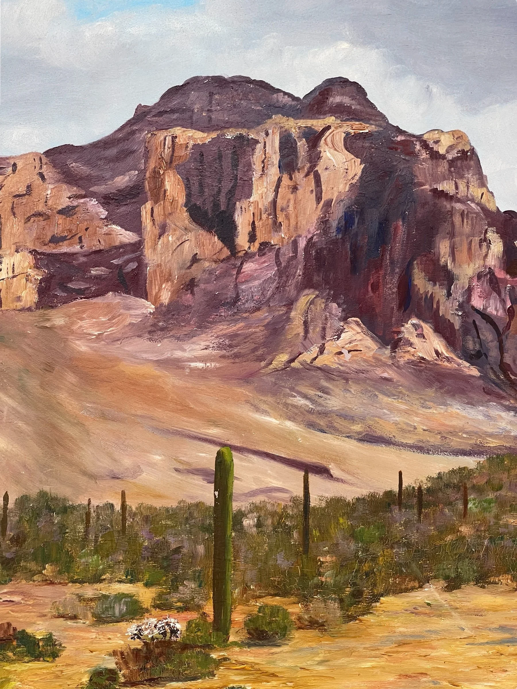 Vintage large framed original desert landscape oil painting signed by artist, Jean Tillman. Painting features an arid desert with cactus, mountains in the background all under a party cloudy sky.