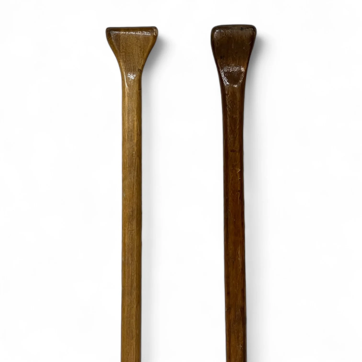 Handles of a vintage pair of rustic wooden boat oars paddles with a clear gloss coating.