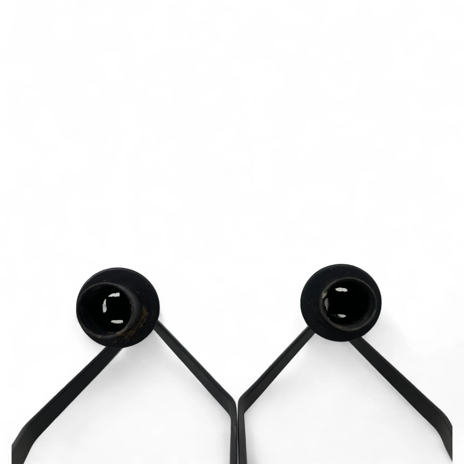 Pair of black metal wall mount candle holders in the shape of an elongated diamond, that holds a taper candle