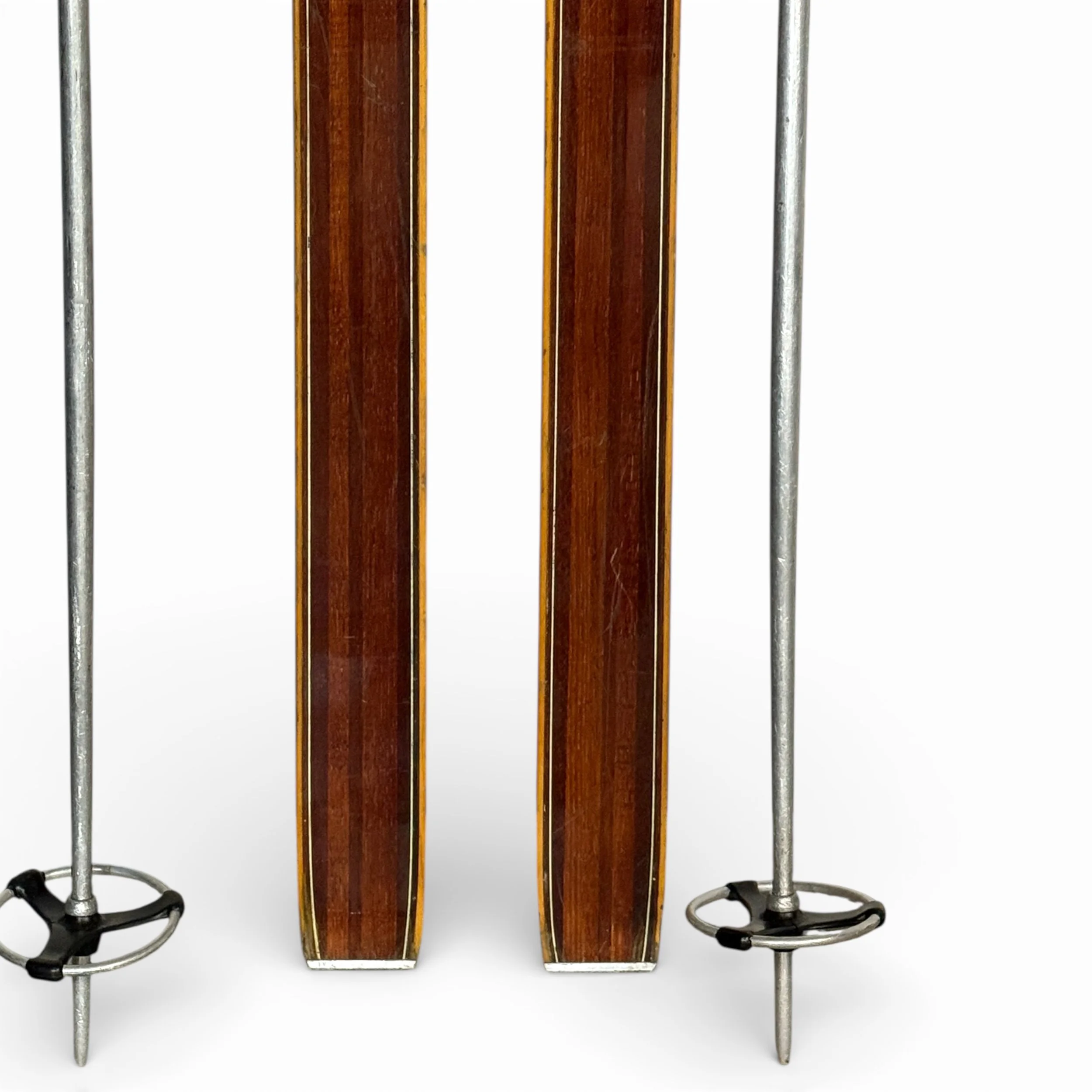 close up view of bottom half of vintage wooden skis with ski poles