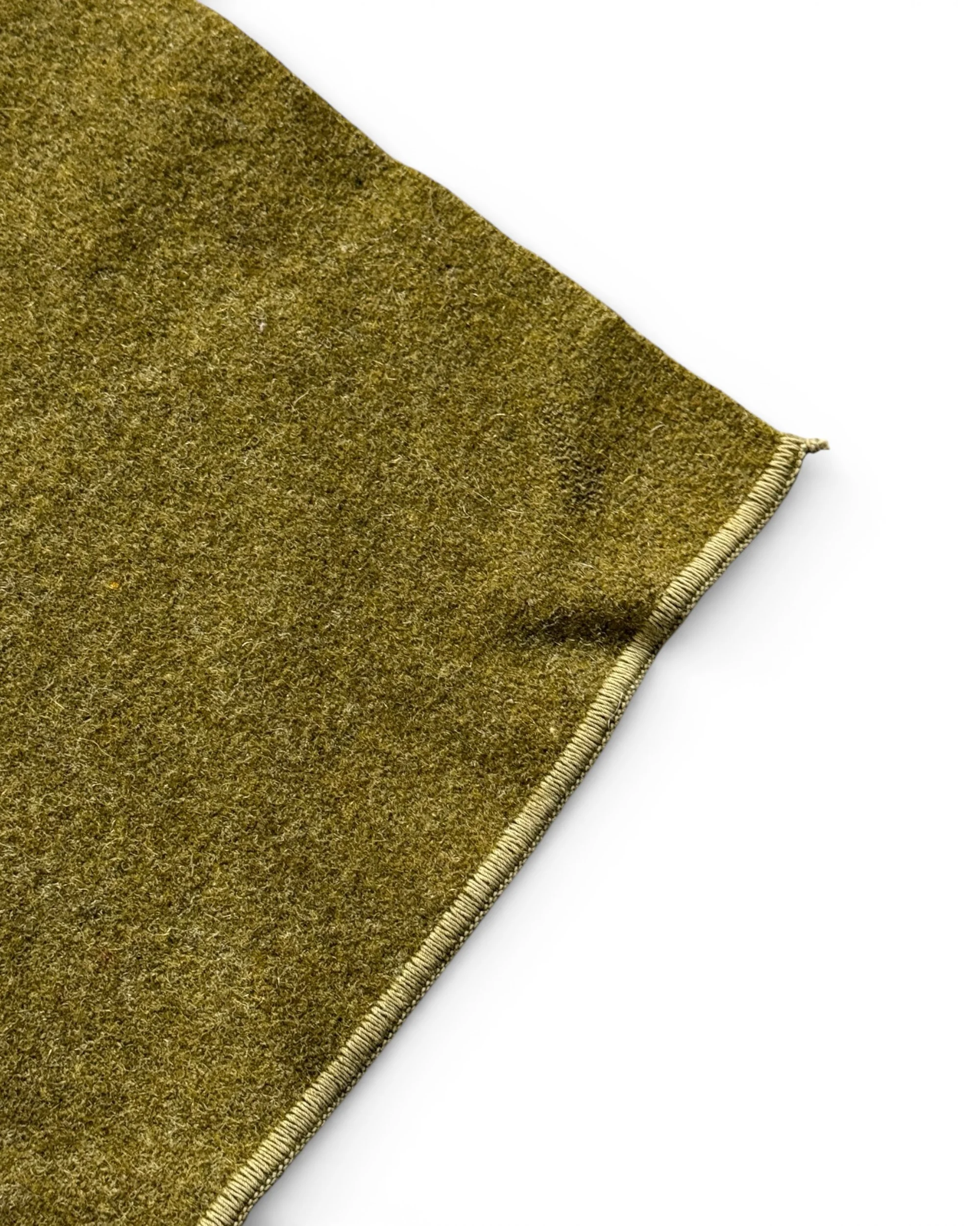 close up view of corner on vintage US military olive drab wool blanket showing the detailed fibers and zig zag stitched edging