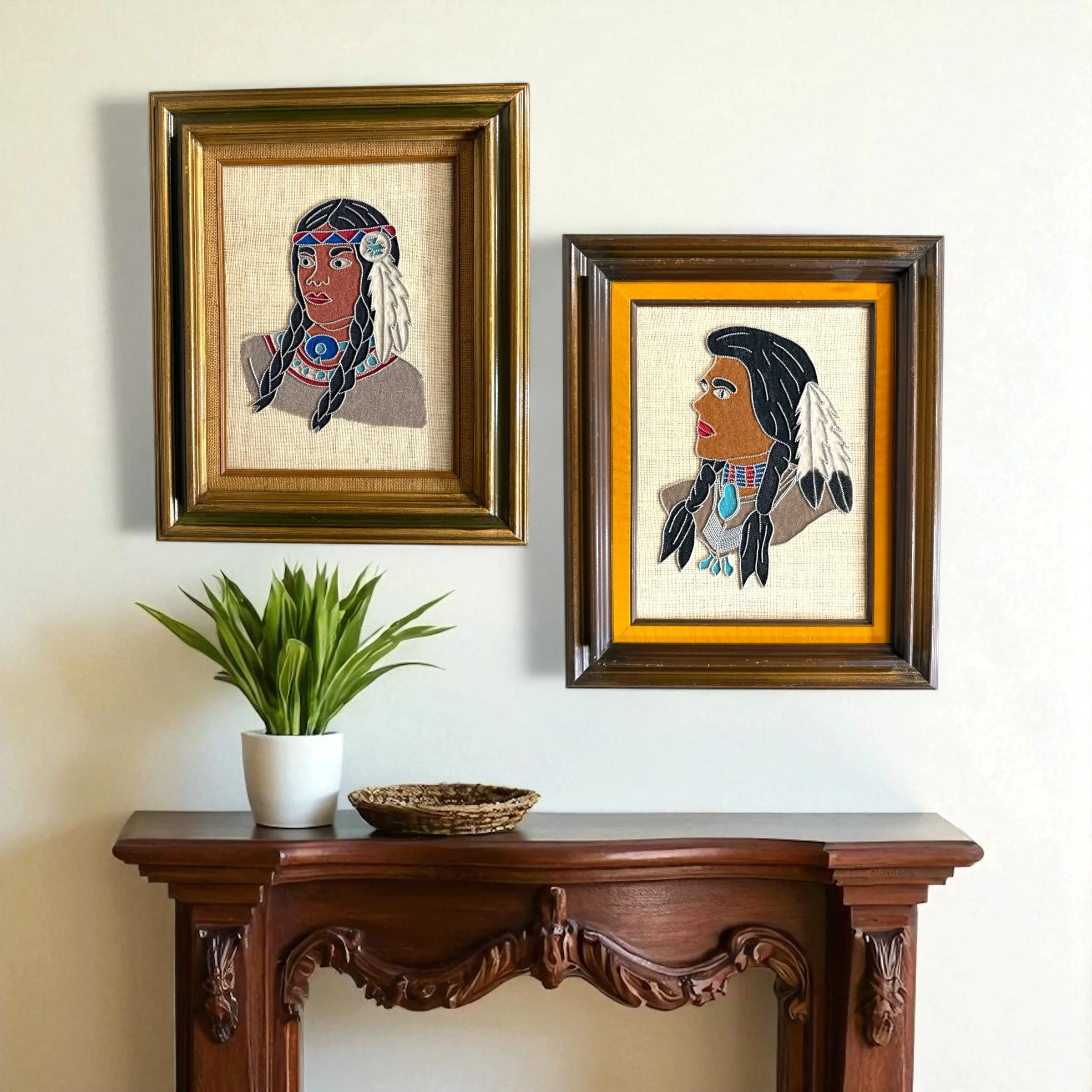 Two framed portraits of Native American figures. Feature detailed sand on a tan background, with gold and brown frames. The figures have dark hair, feather accents, and colorful beaded jewelry.