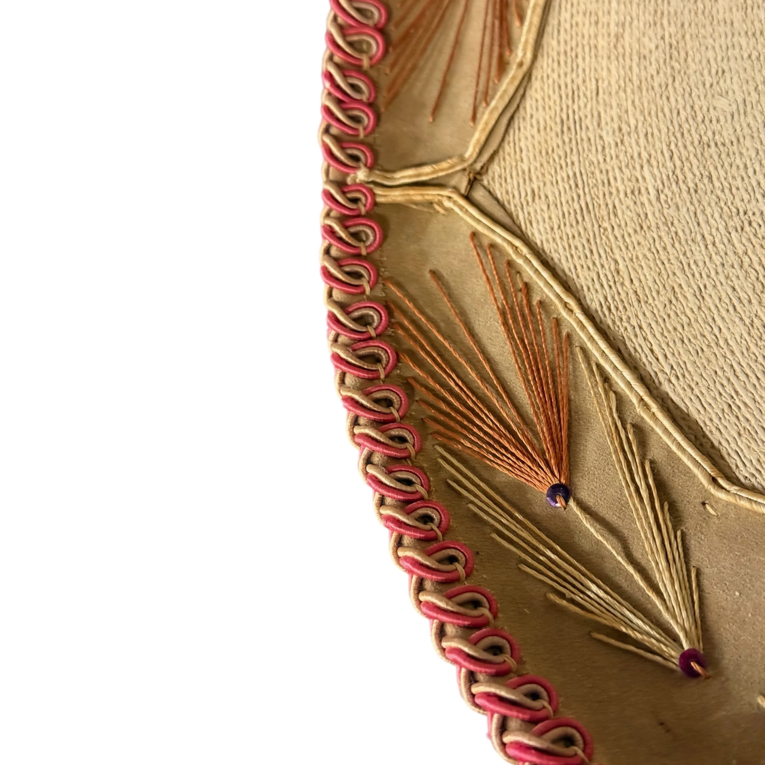 close up view of embroidered details in light brown and pink on a vintage sombrero made of palm fiber