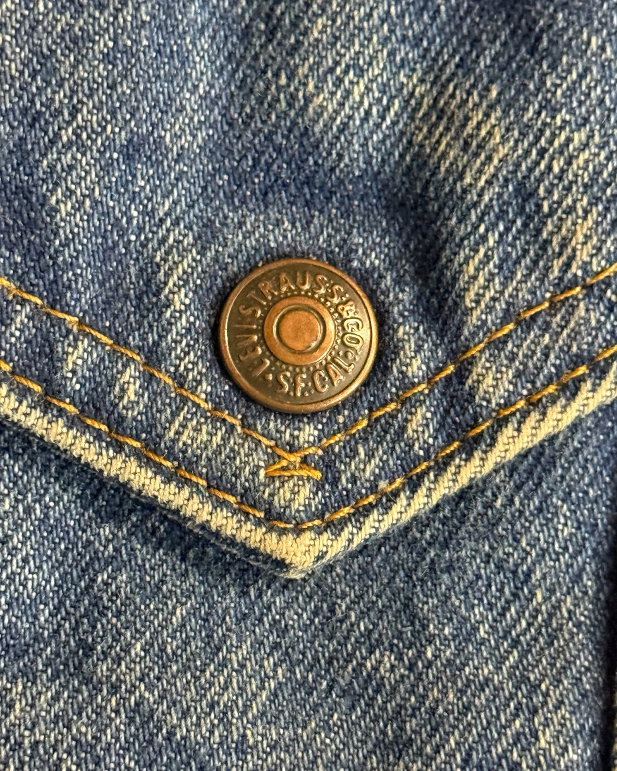 close up of button on snap front pocked on vintage 1980s Levi's denim sherpa trucker jacket.