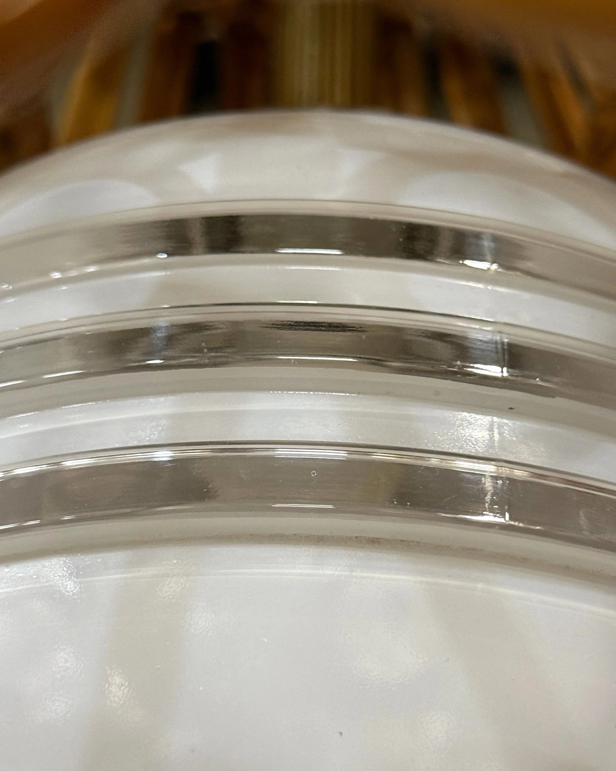 close up view of vintage white glass globe that has 3 bands of clear glass around the circumference