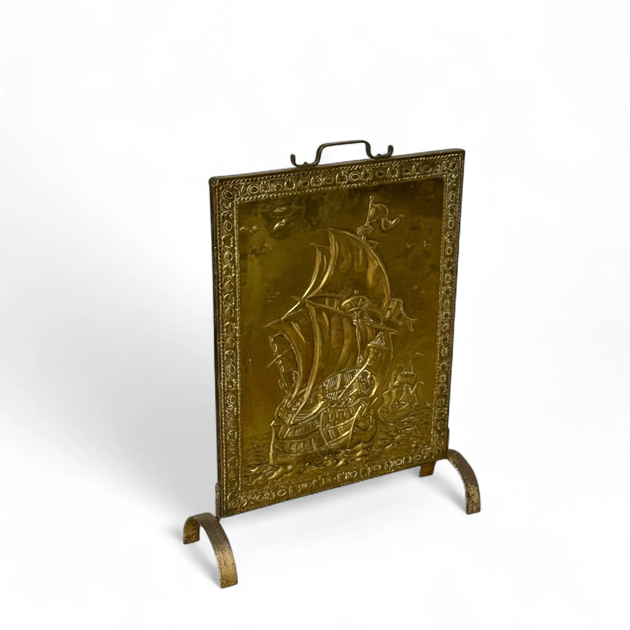 Vintage brass fireplace screen with handle with embossed Galleon ship sailing scene, mid century nautical home decor accent.