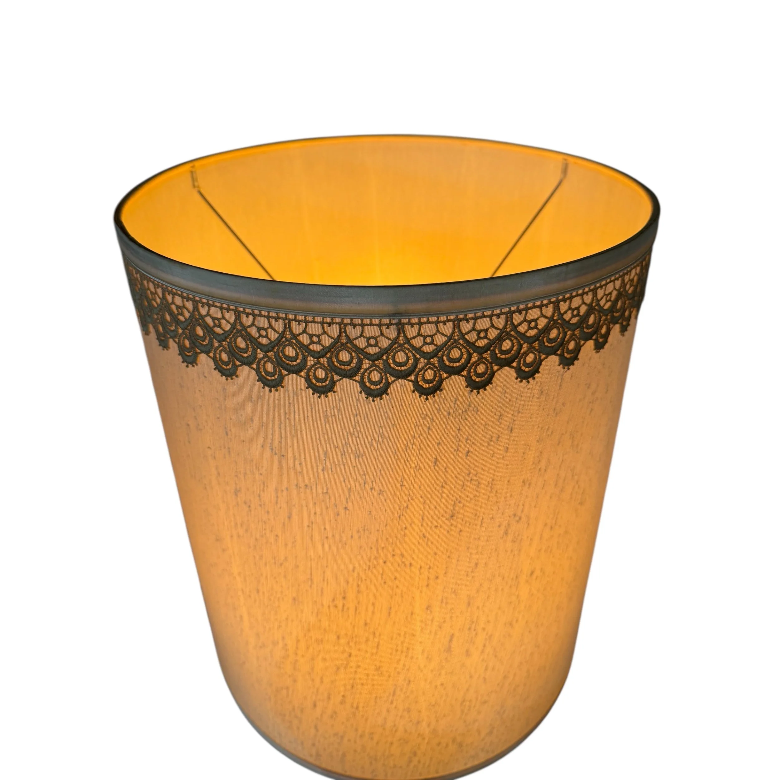 Full view of vintage lace trimmed drum lamp shade with light on showing the warm ambient glow