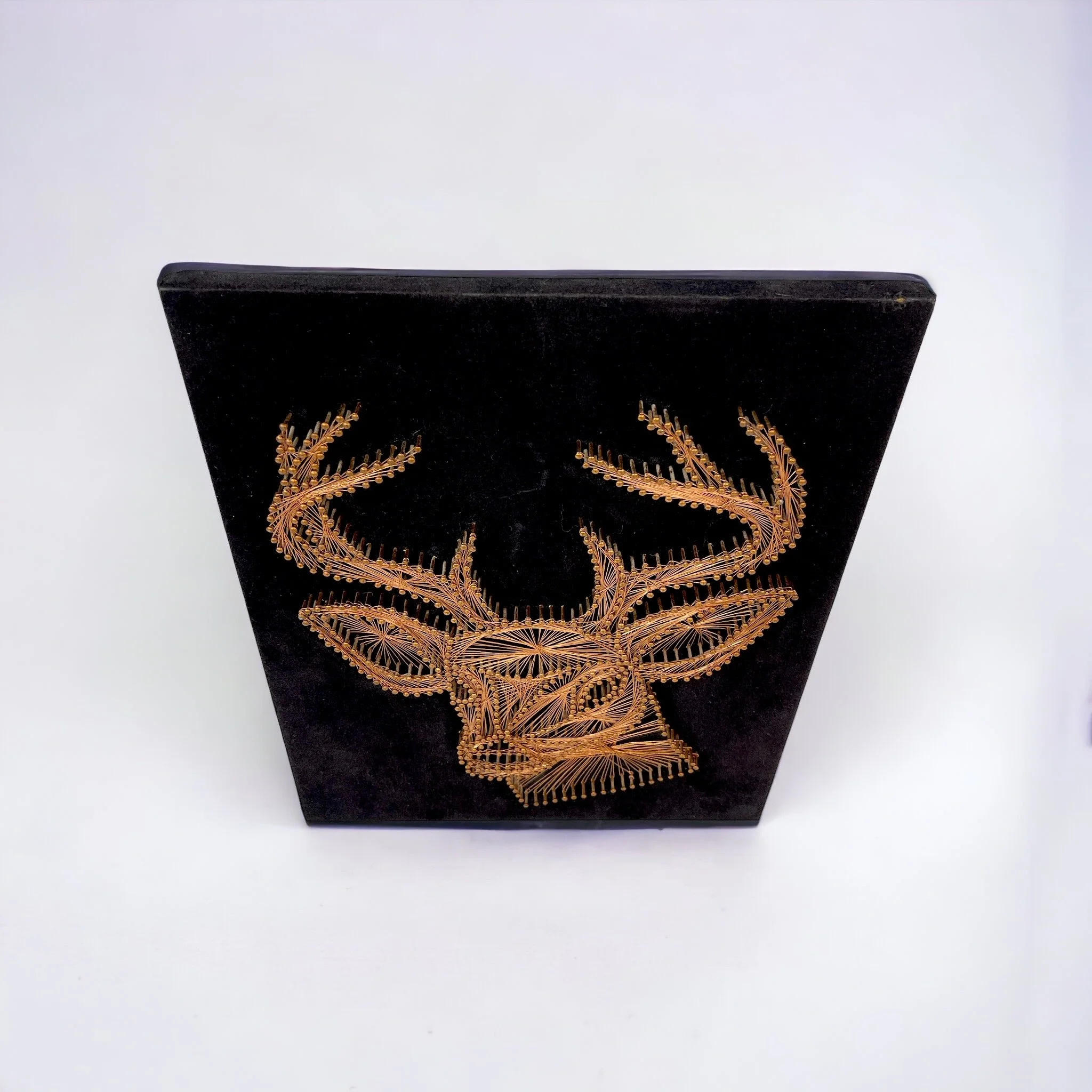 Vintage copper string art of a male deer, buck, on a black velvet board.