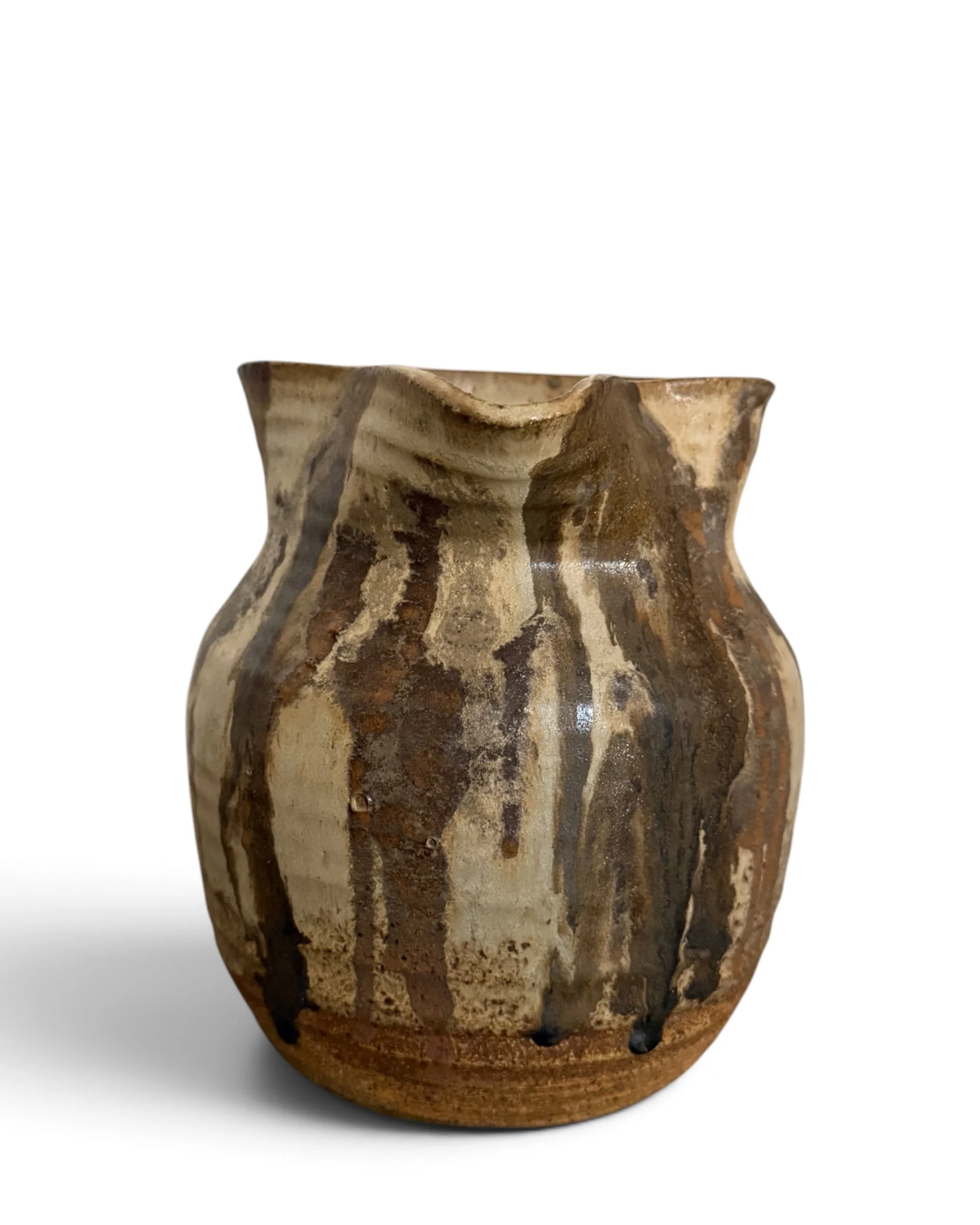 Front view of a vintage ceramic pottery pitcher featuring warm brown, tan, cream, and earthy drip glaze