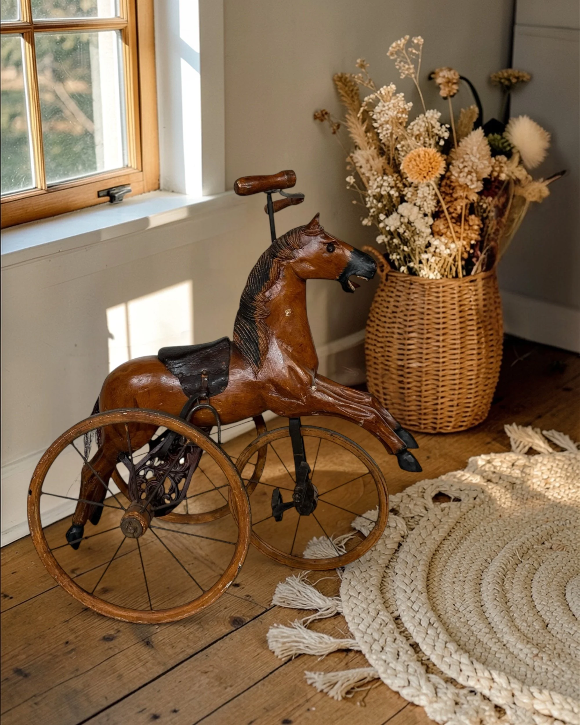 wooden horse pedal tricycle with iron wheels and steering handle styled in a country farmhouse living room