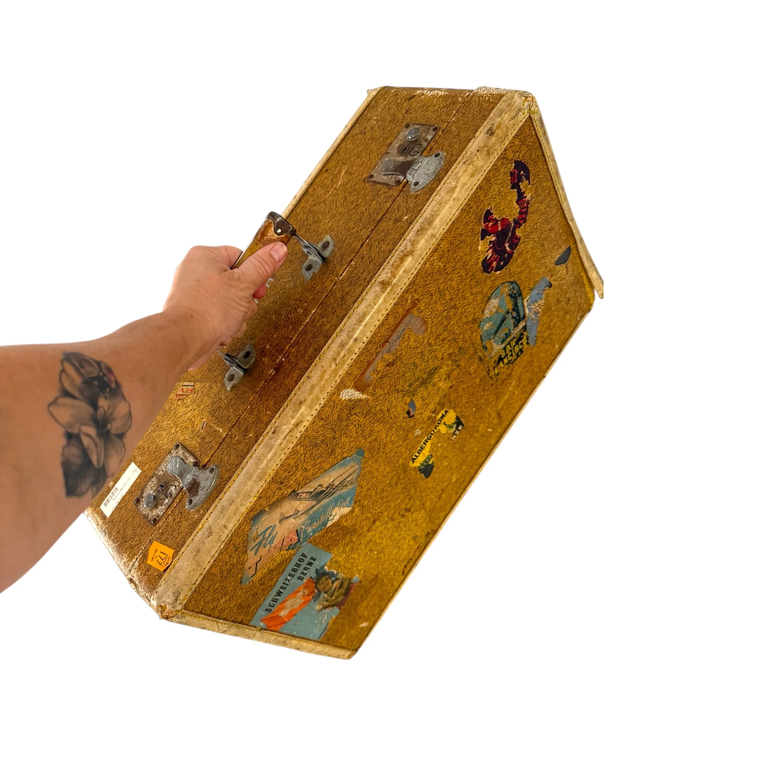 Antique Wheary Luggage travel suitcase with original worldwide travel stickers shown in a woman's hand with arm extended