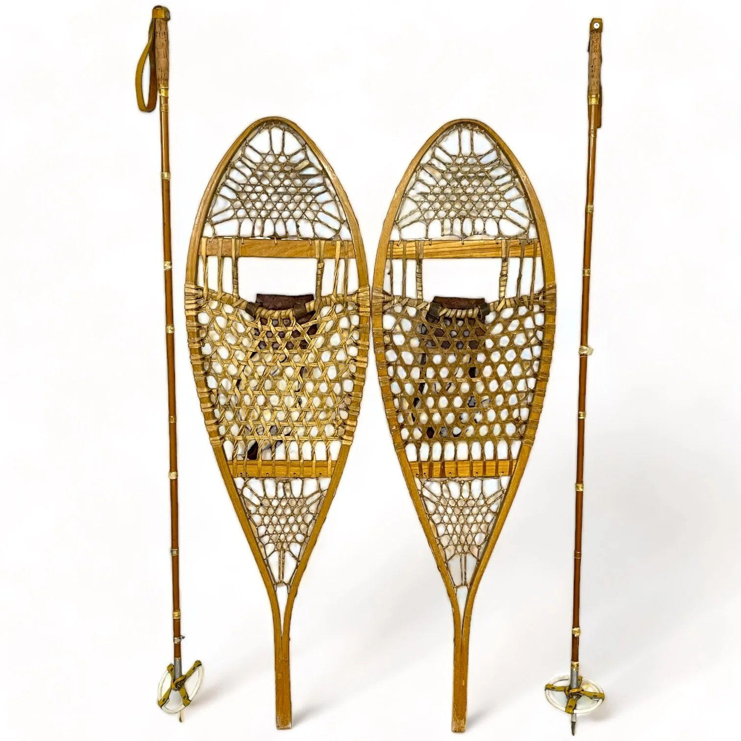 Pair of vintage wooden snowshoes with ski poles made of bamboo and cork - classic rustic winter gear perfect for cabin decor, lodge style, or outdoor adventures.