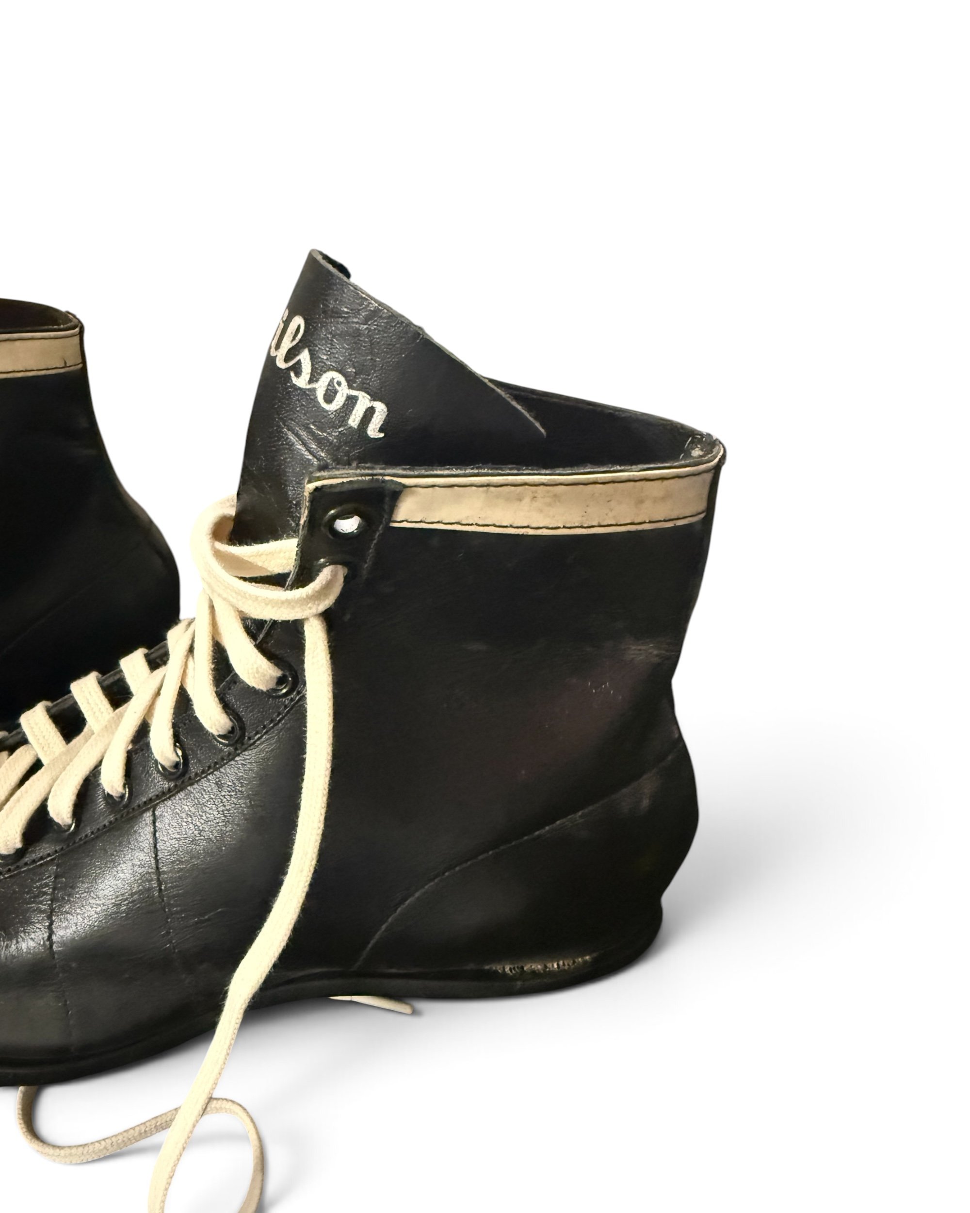 Close-up of Wilson branding on vintage black leather 1950s football cleats