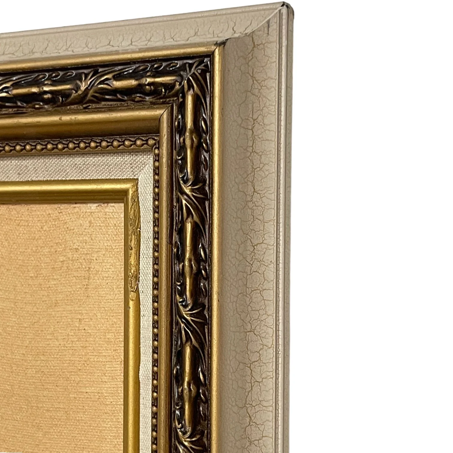 Close up view of the corner of a vintage white and gold ornate frame.