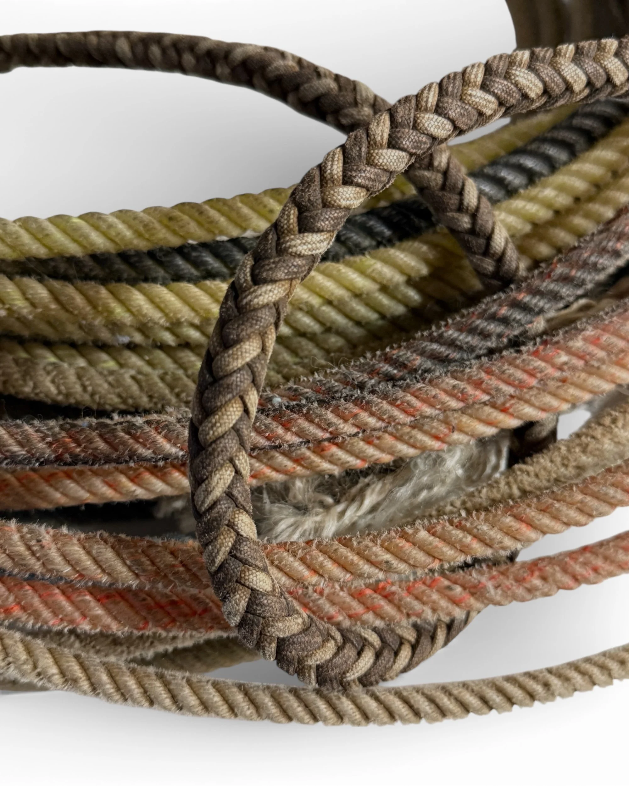 close up of various vintage lasso ropes showing detailed chevron patterns and colors including brown, tan, orange, and yellow