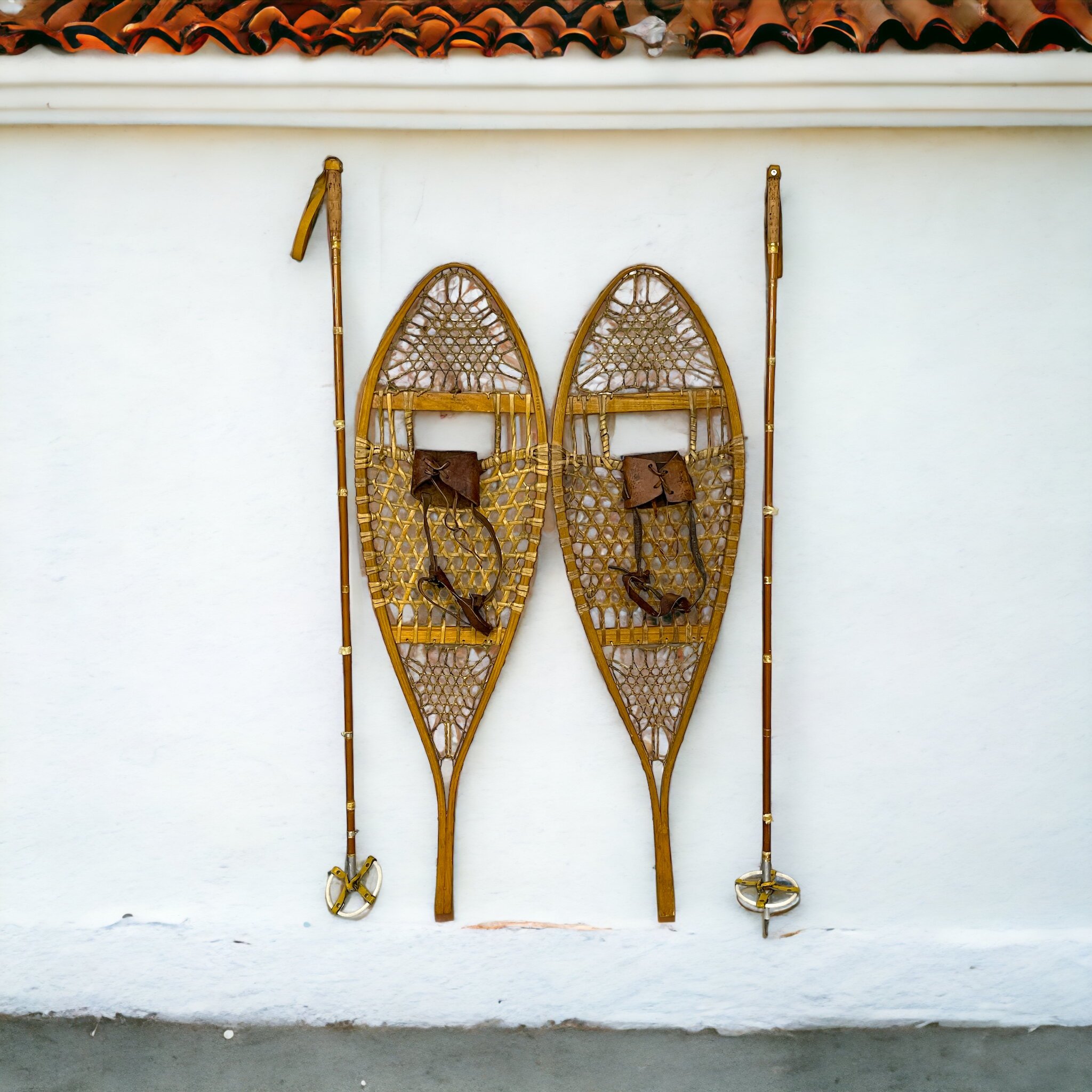 Pair of vintage wooden snowshoes with ski poles made of bamboo and cork - classic rustic winter gear perfect for cabin decor, lodge style, or outdoor adventures.