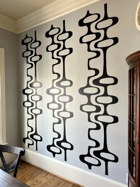 Mid Century geometric pattern wall decal by Wall Star Graphics shown in black on a light grey wall in a dining room.