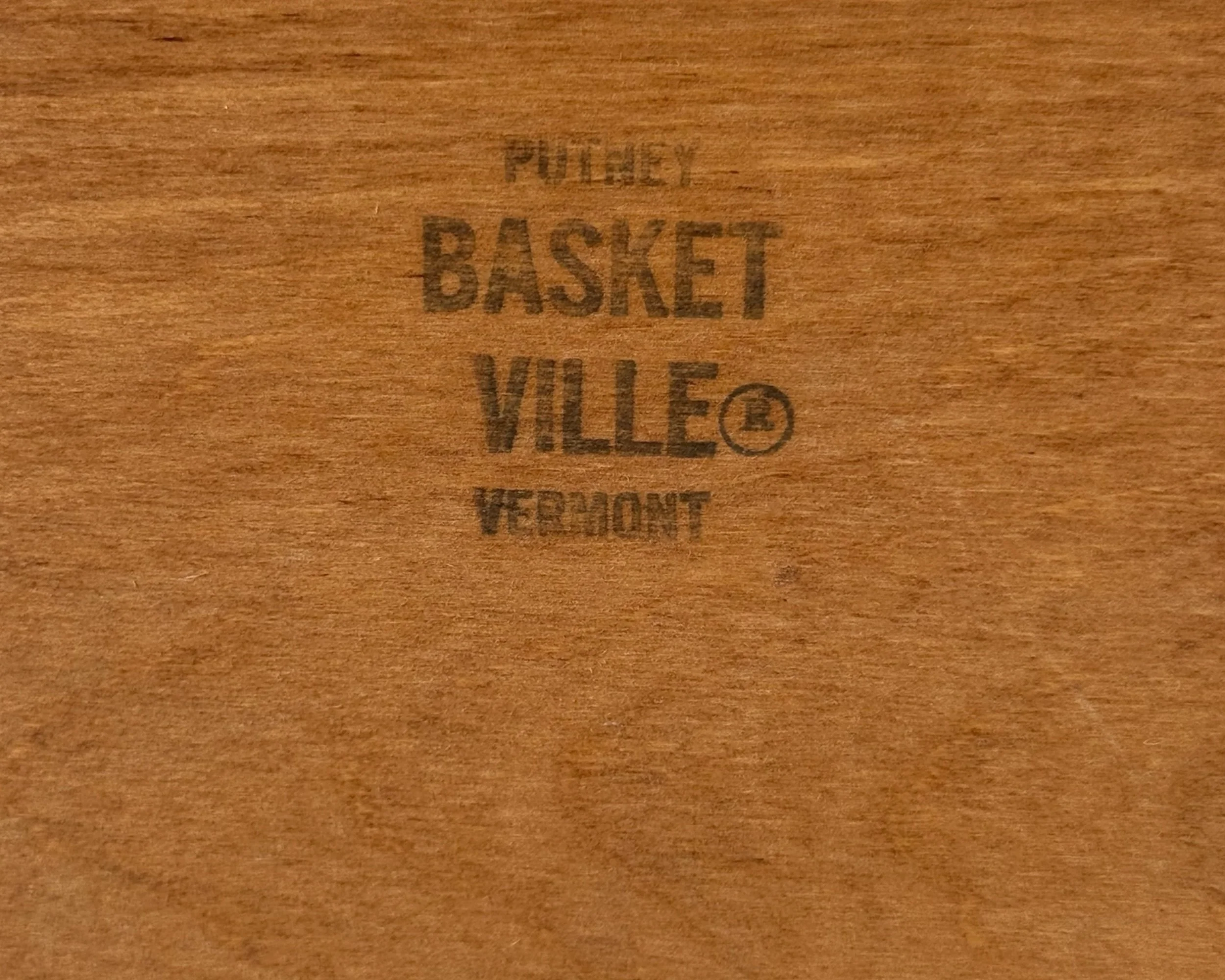 close up view of stamped logo on the lid of a picnic basket that reads Basketville Putney, Vermont