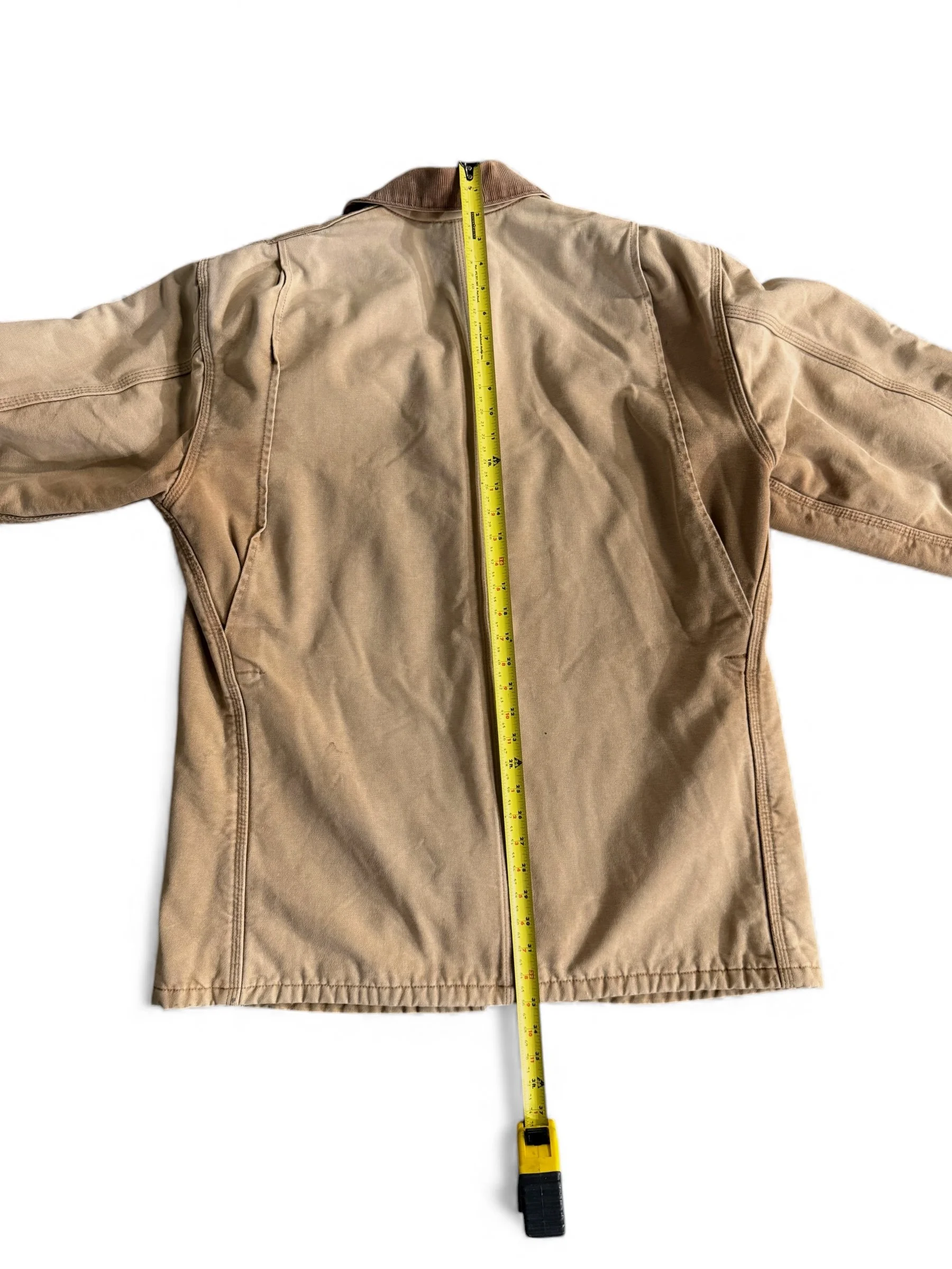 Full back view of a vintage Carhartt chore jacket with a ruler showing measurements