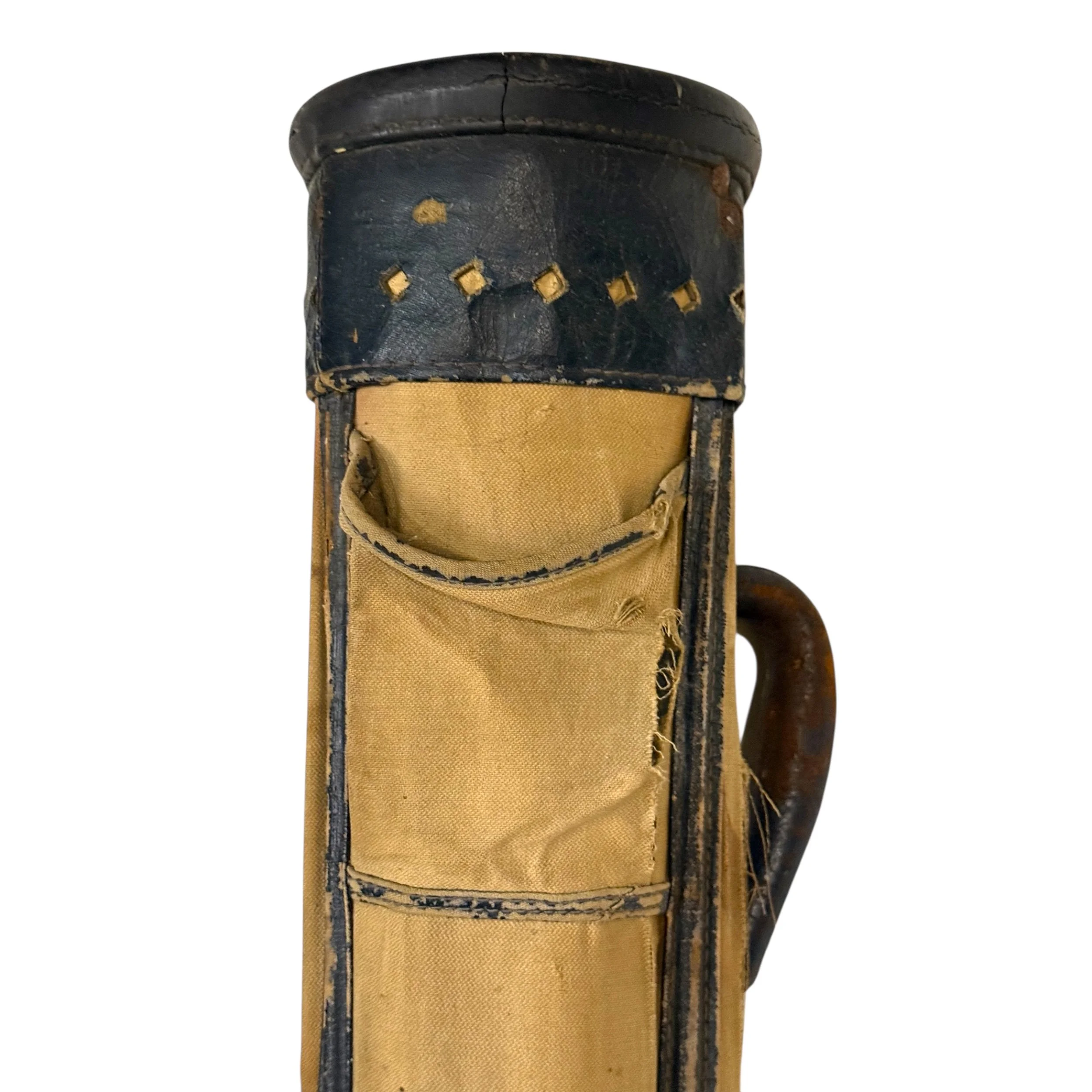 Close up view of top half of antique golf bag. Bag features leather accents with diamond shaped cutouts, leather carrying handle, and canvas body.