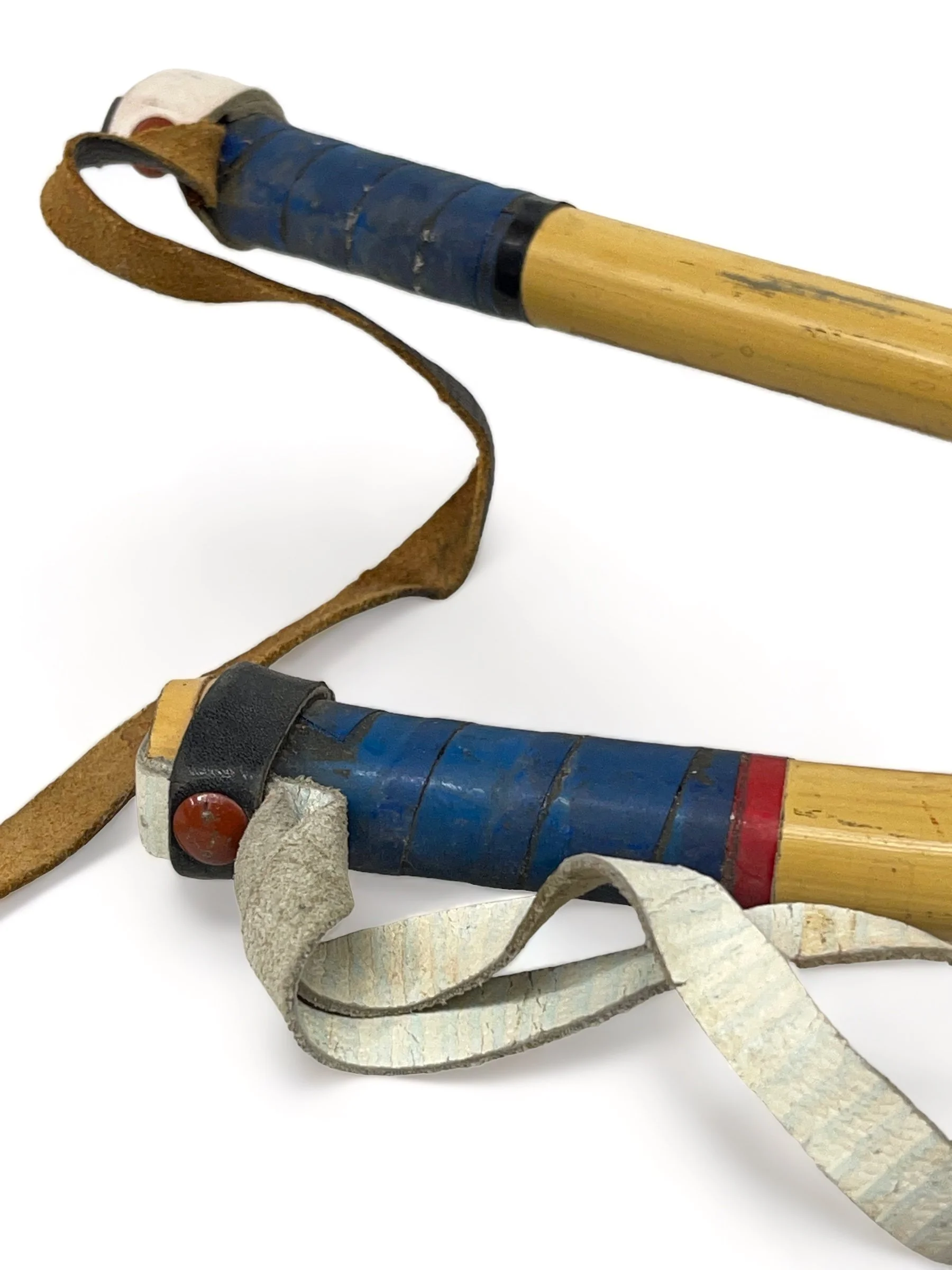 Close up view of the handles on a pair of kids vintage bamboo ski poles.