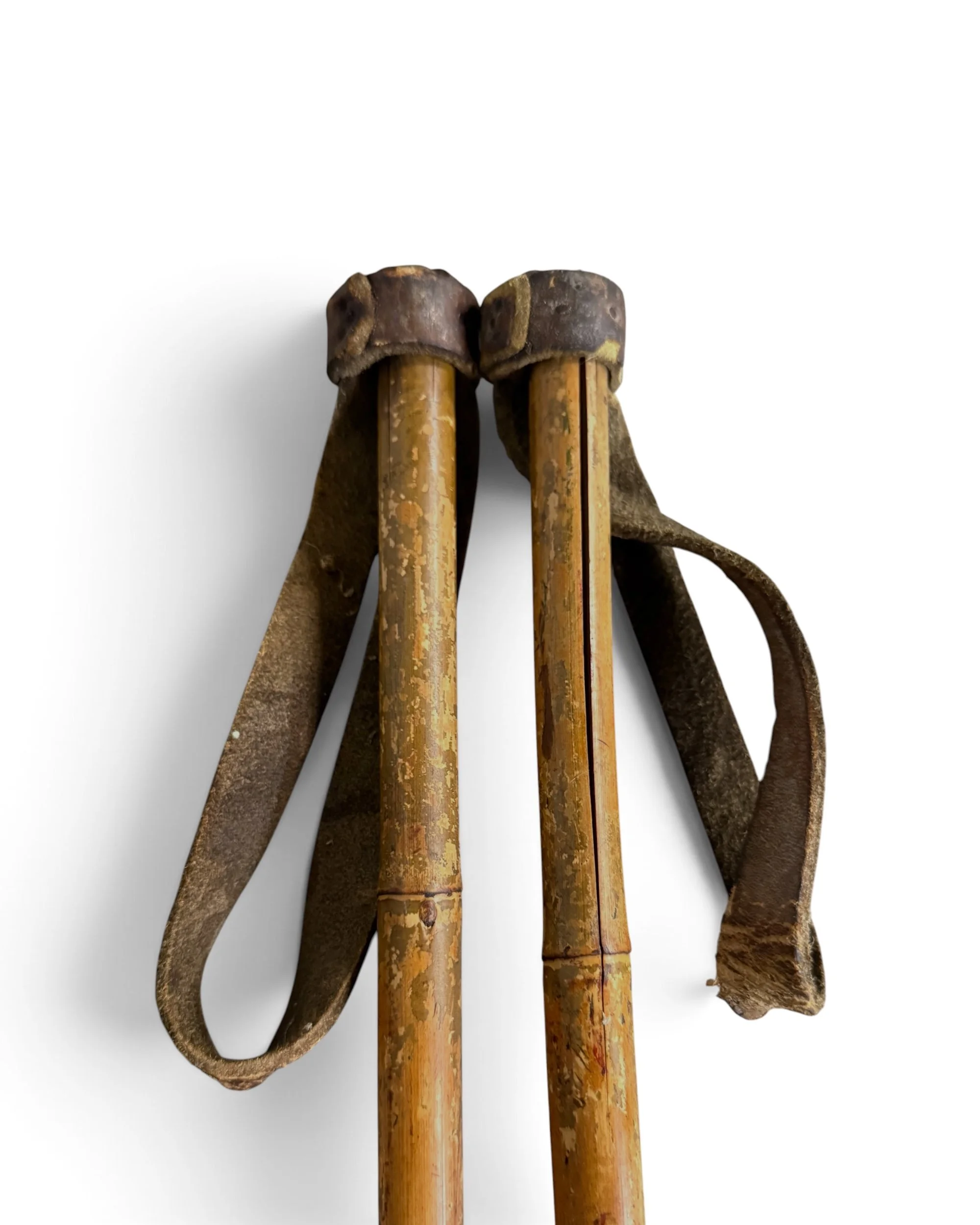close up view of leather wrist straps on pair of vintage bamboo ski poles