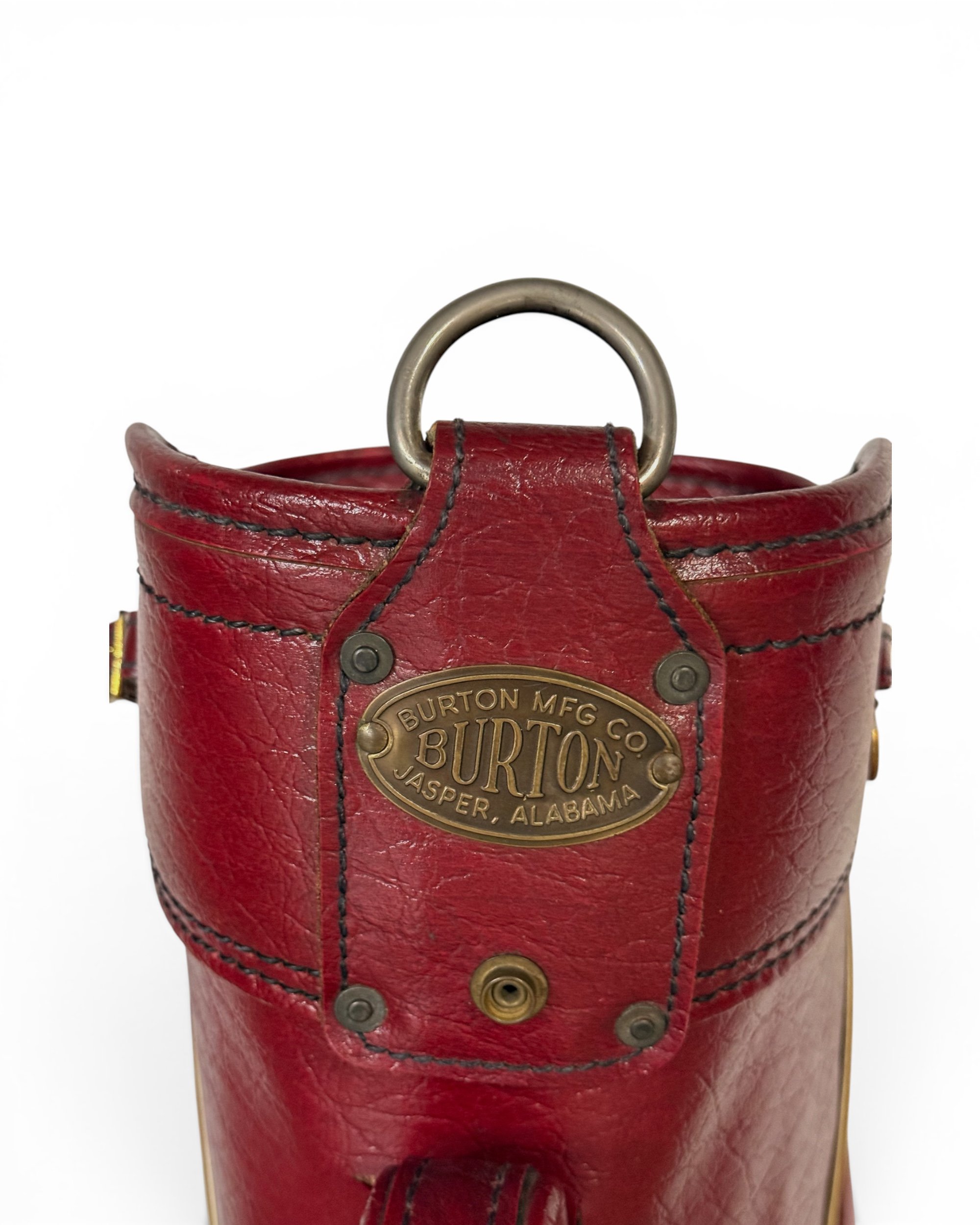 close up view of logo on a vintage red vinyl golf bag that reads "Burton Mfg. Co., Burton, Jasper, Alabama"