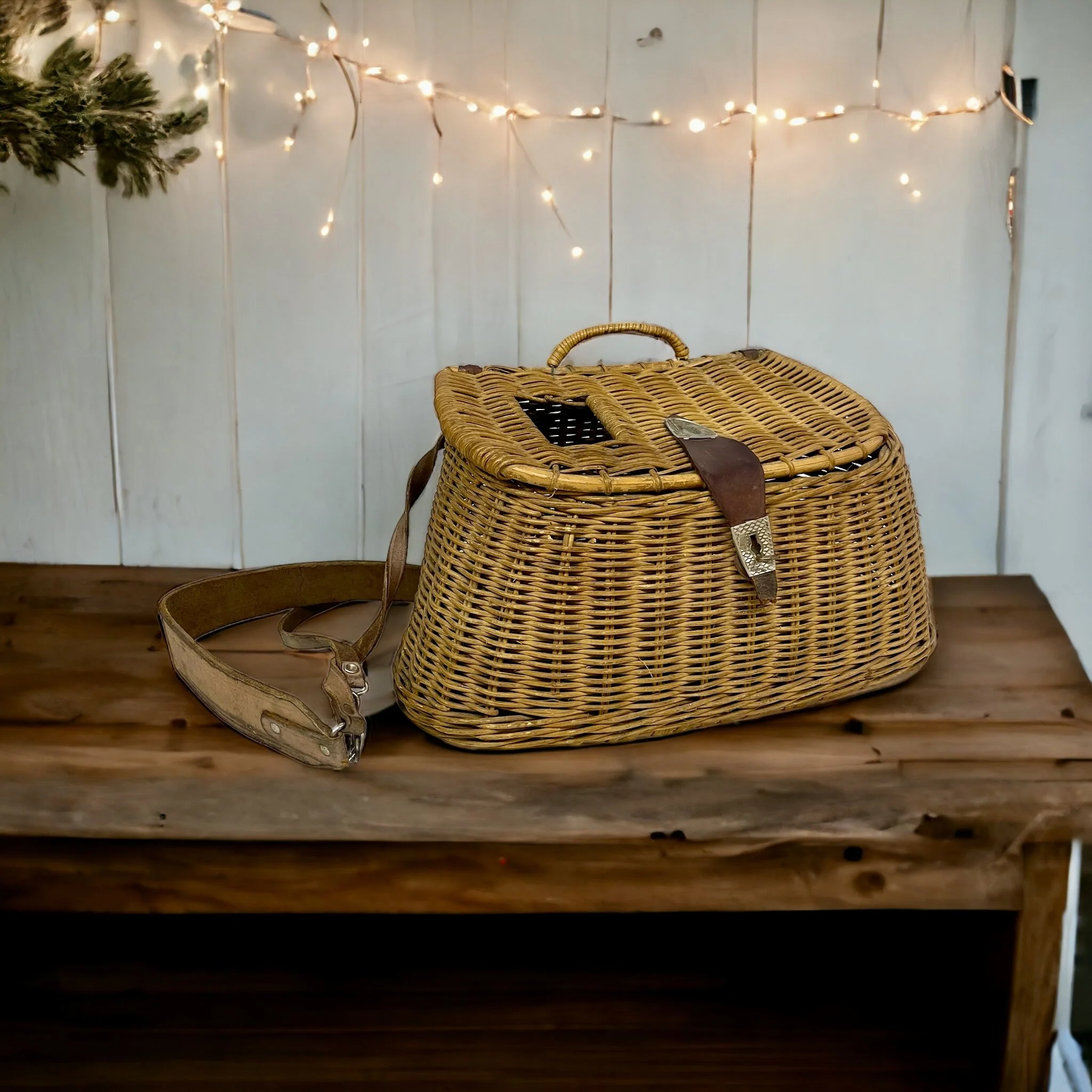 Vintage wicker fishing creel with adjustable leather shoulder strap and leather and metal lid clasp shaped as a fish. Great rustic decor for cabin or lodge.